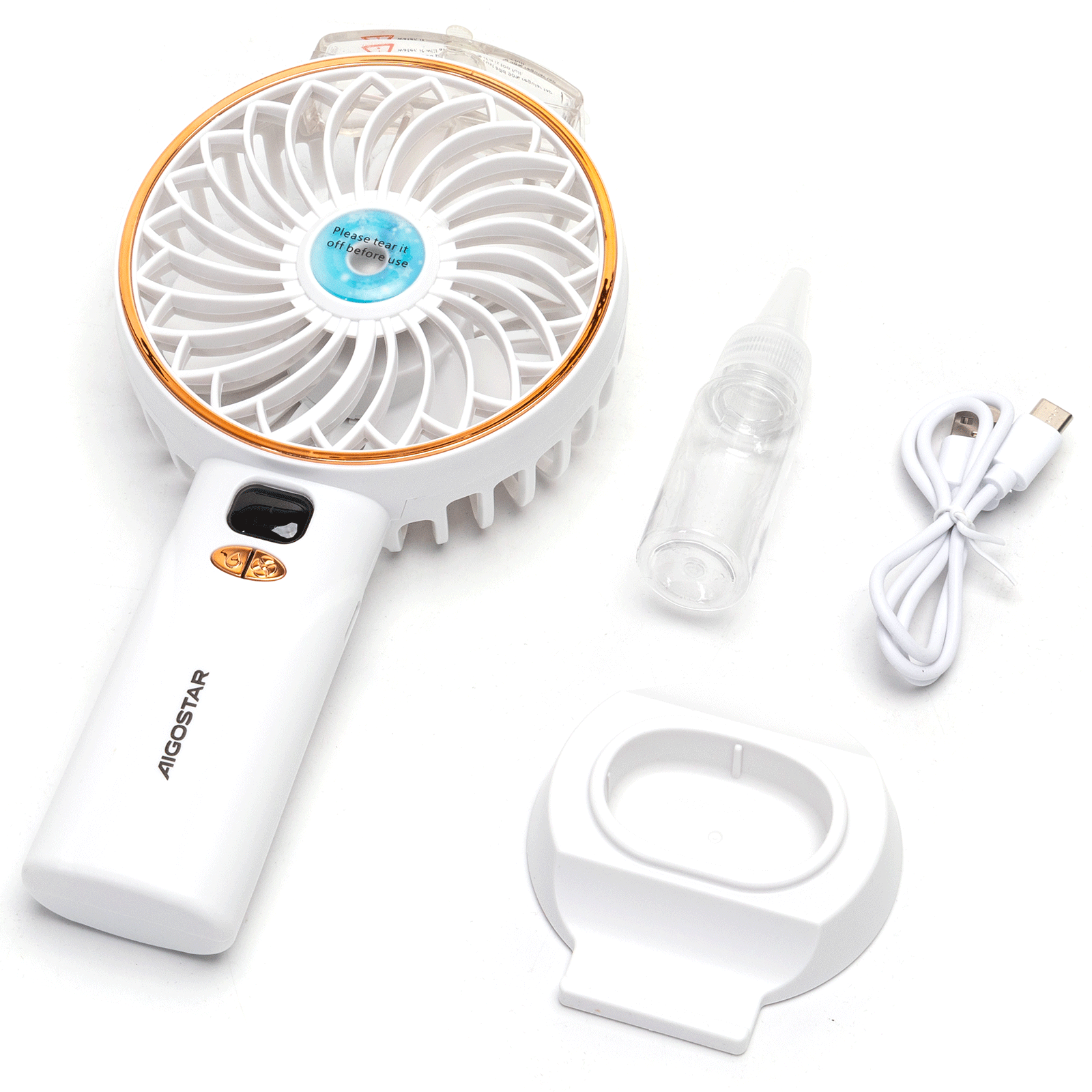 Ventilatore portatile bianco con finiture dorate, accessori come flacone spray, cavo di ricarica e supporto su superficie bianca.