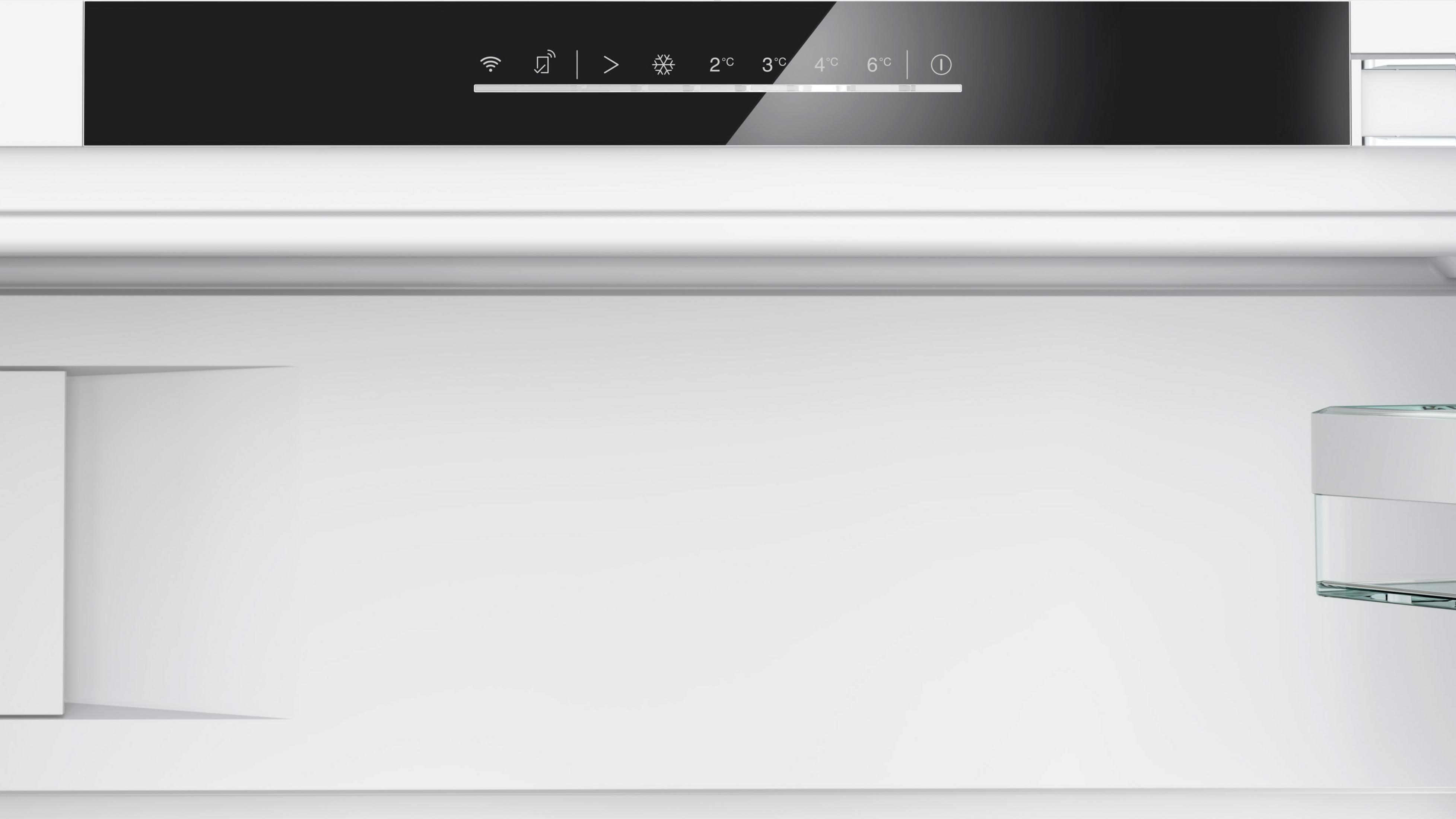 In einem weißen Kühlschrank. Die obere Platte hat Symbole und Temperaturen. Auf der rechten Seite befindet sich ein Glasregal. Leerer Raum dominiert die Ansicht.