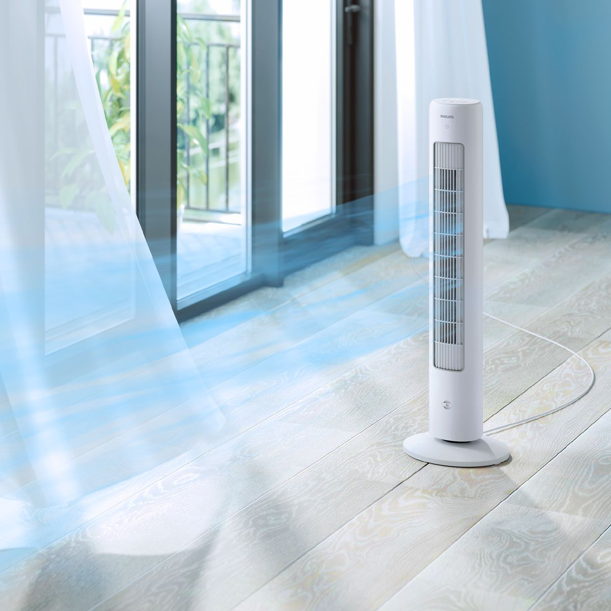 Biały wentylator wieżowy stoi na drewnianej podłodze. Niebieskie powietrze przepływa z niego w kierunku otwartych drzwi. Zasłony i niebieska ściana w tle.