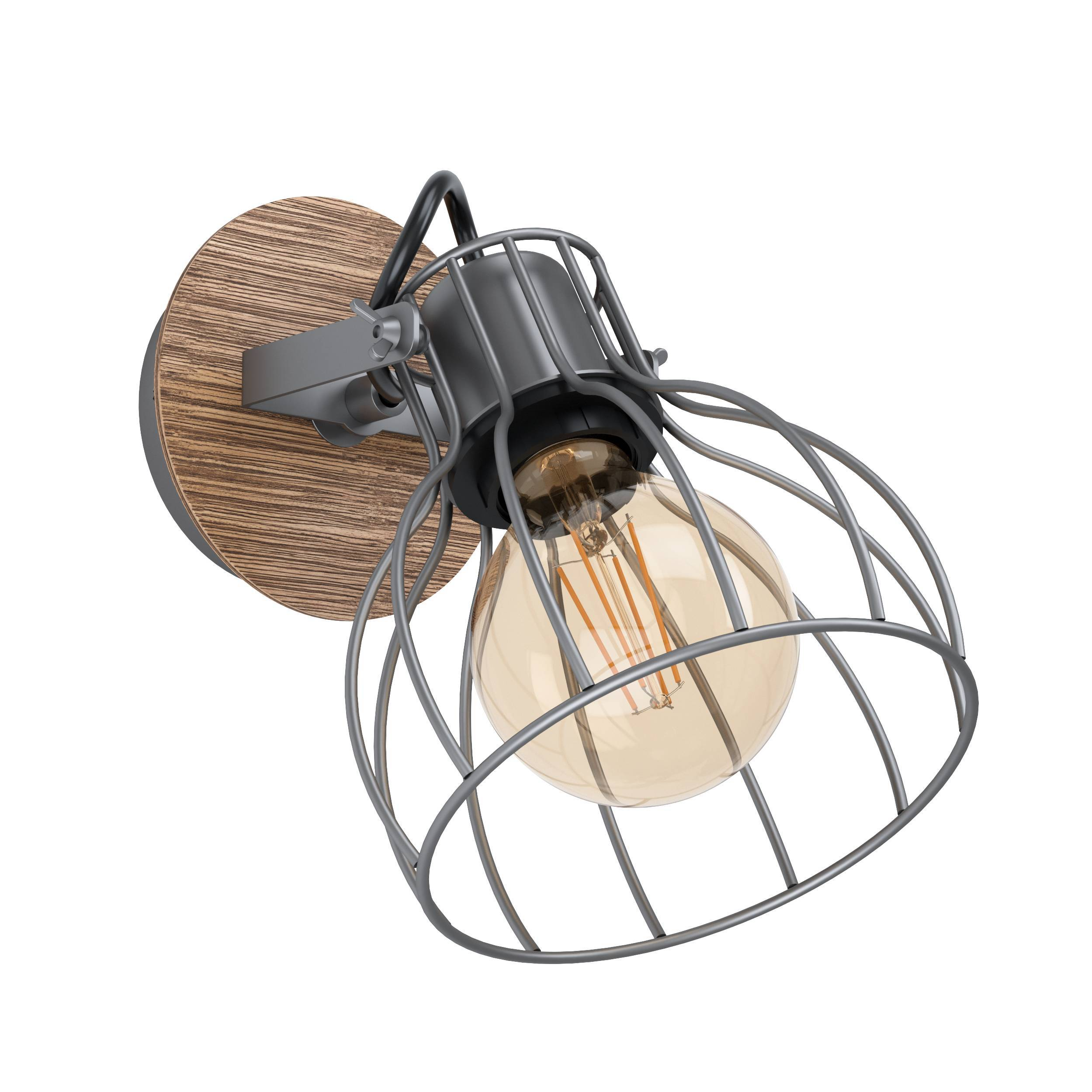 Una lampada da parete con base in legno, braccio in metallo e lampadina a gabbia. La lampadina è accesa.