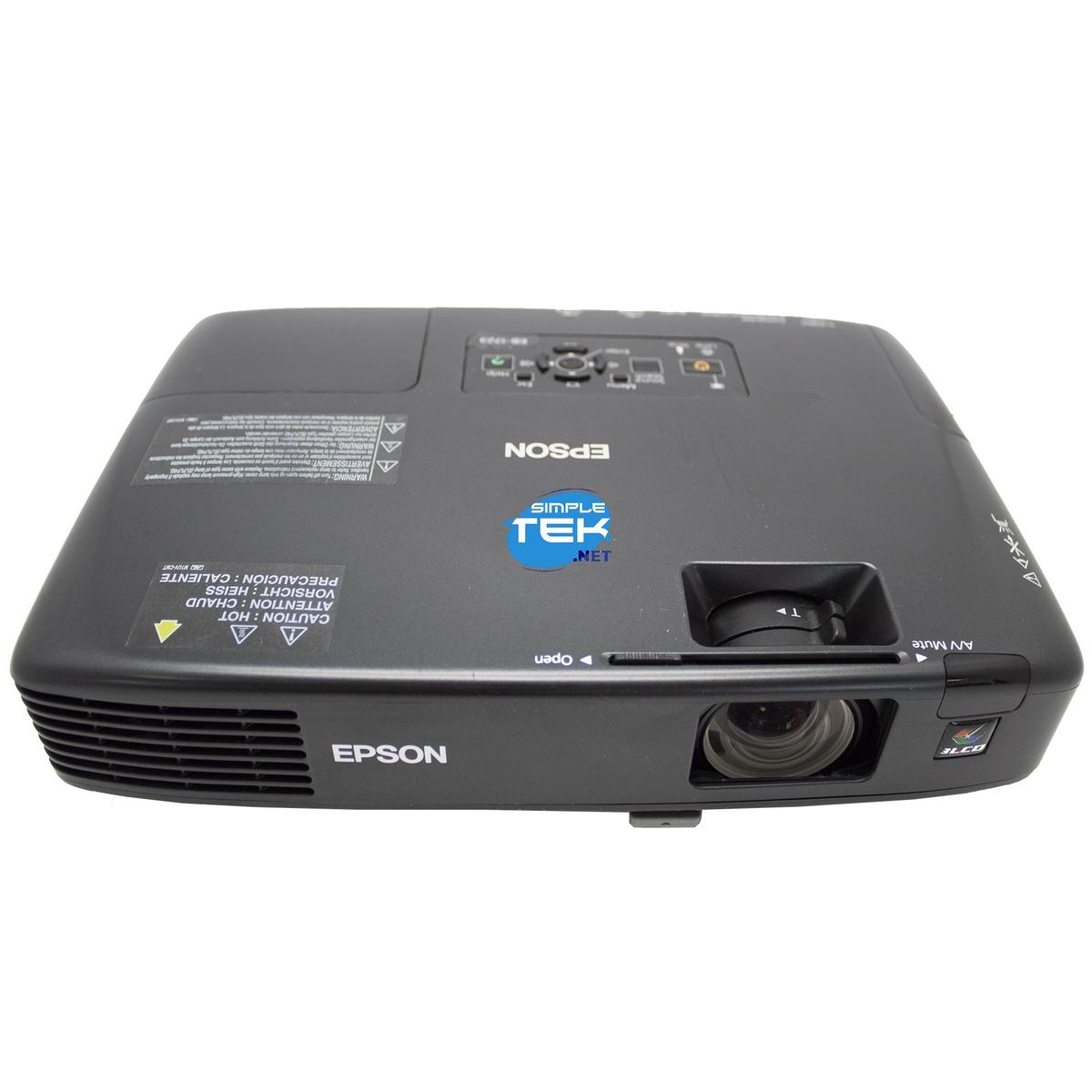 Un proiettore Epson nero con etichette e lente è su una superficie bianca. Il logo Epson e altri simboli sono visibili.