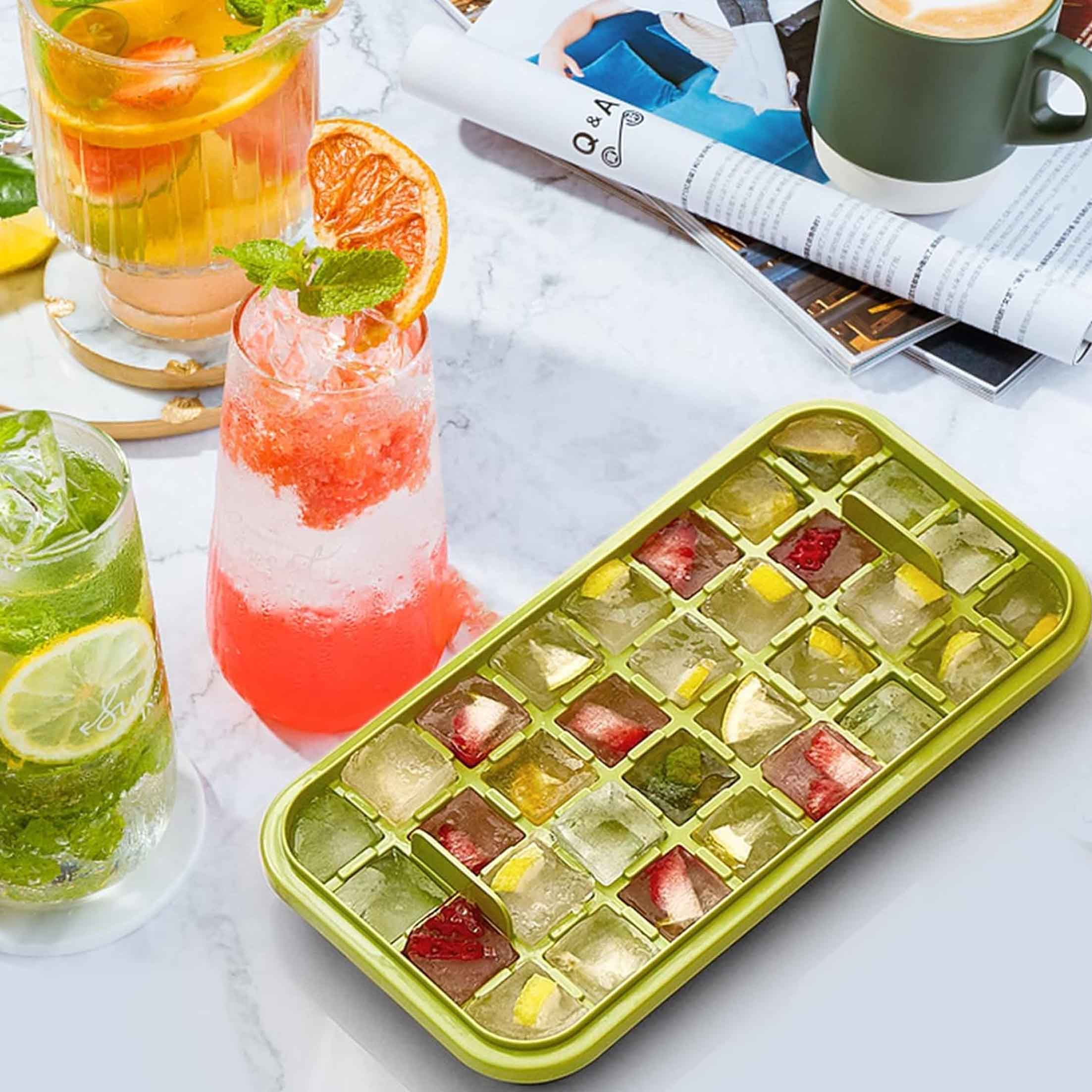 Ein Tablett mit Fruchteiswürfeln, Getränken und einer Kaffeetasse auf einem Tisch. Die Eiswürfel enthalten Erdbeeren und Zitrone.