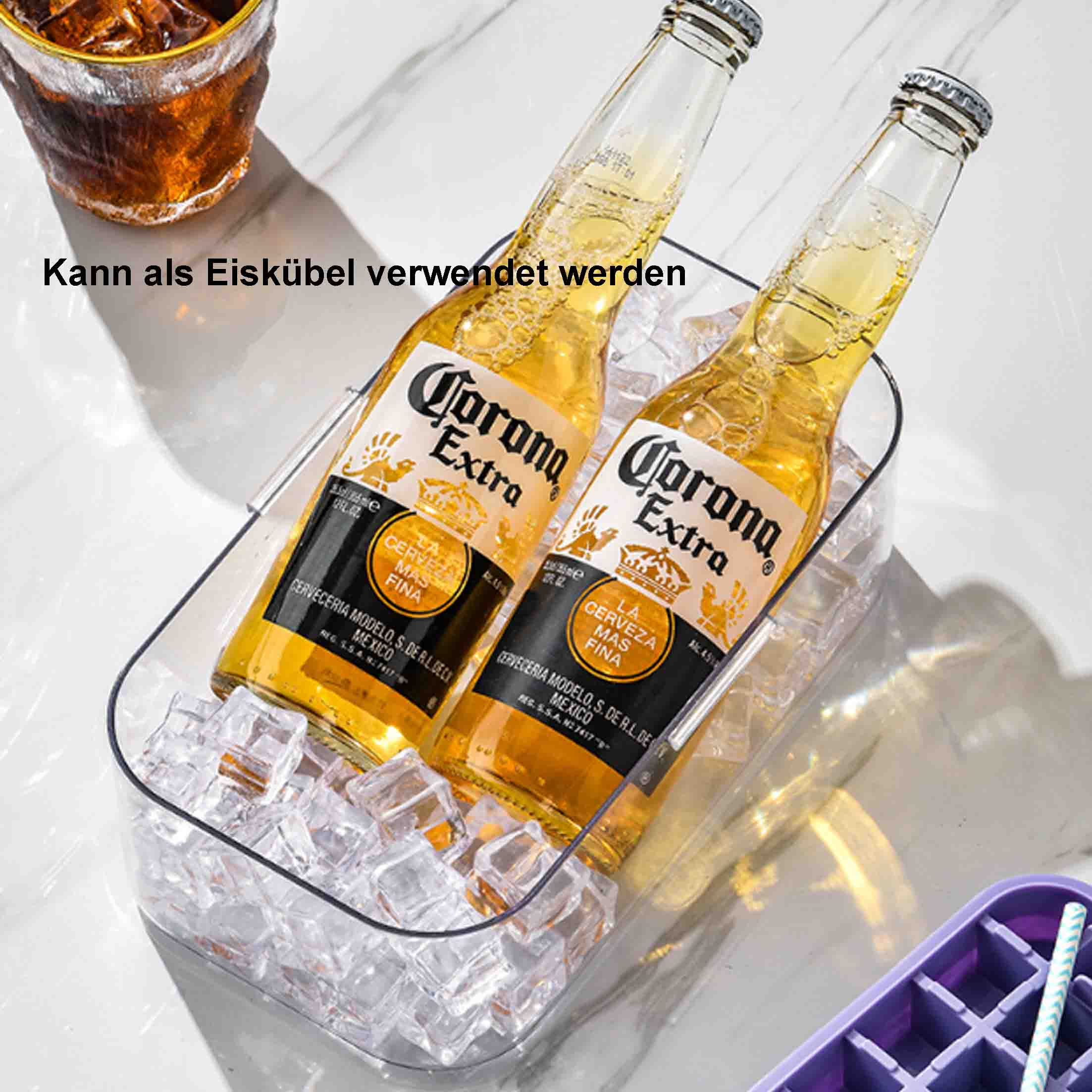 Zwei Corona-Bierflaschen in einem durchsichtigen Eiskübel. Ein Glas mit einem Getränk steht oben links. Eiswürfelschale rechts.