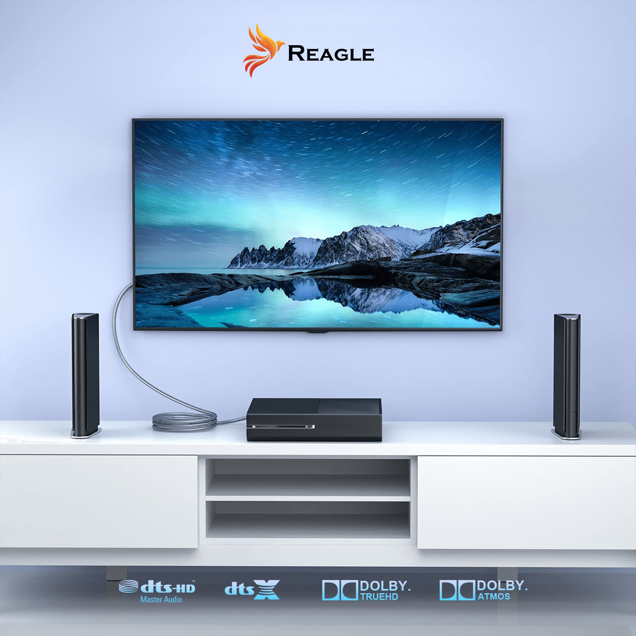 Telewizor z nocnym niebem, z głośnikami, podłączony do odbiornika na białej szafce. Logo Reagle.