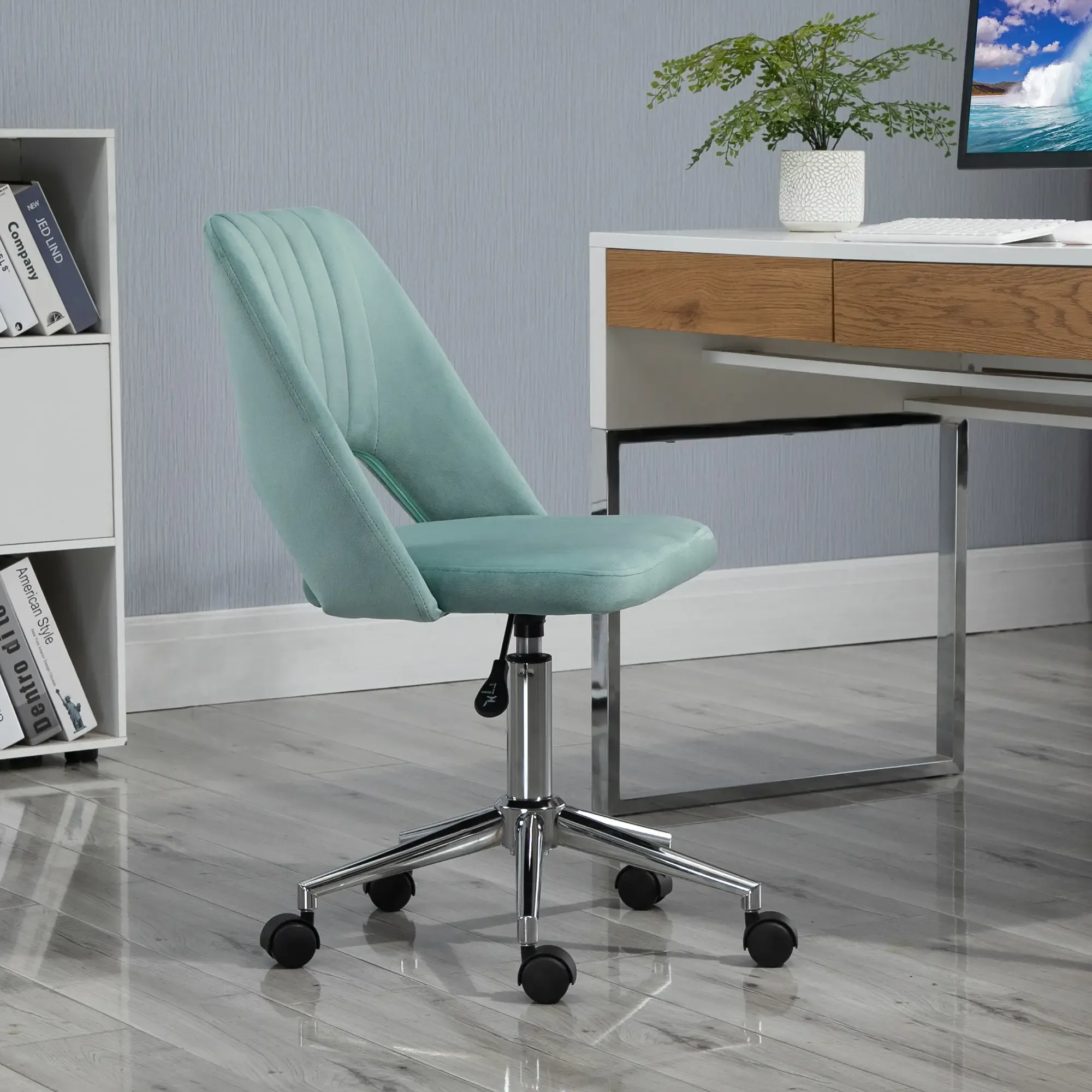 Ein türkisblauer Bürostuhl auf Rollen. Ein weißer Schreibtisch mit Pflanze und Monitor befindet sich hinter dem Stuhl.
