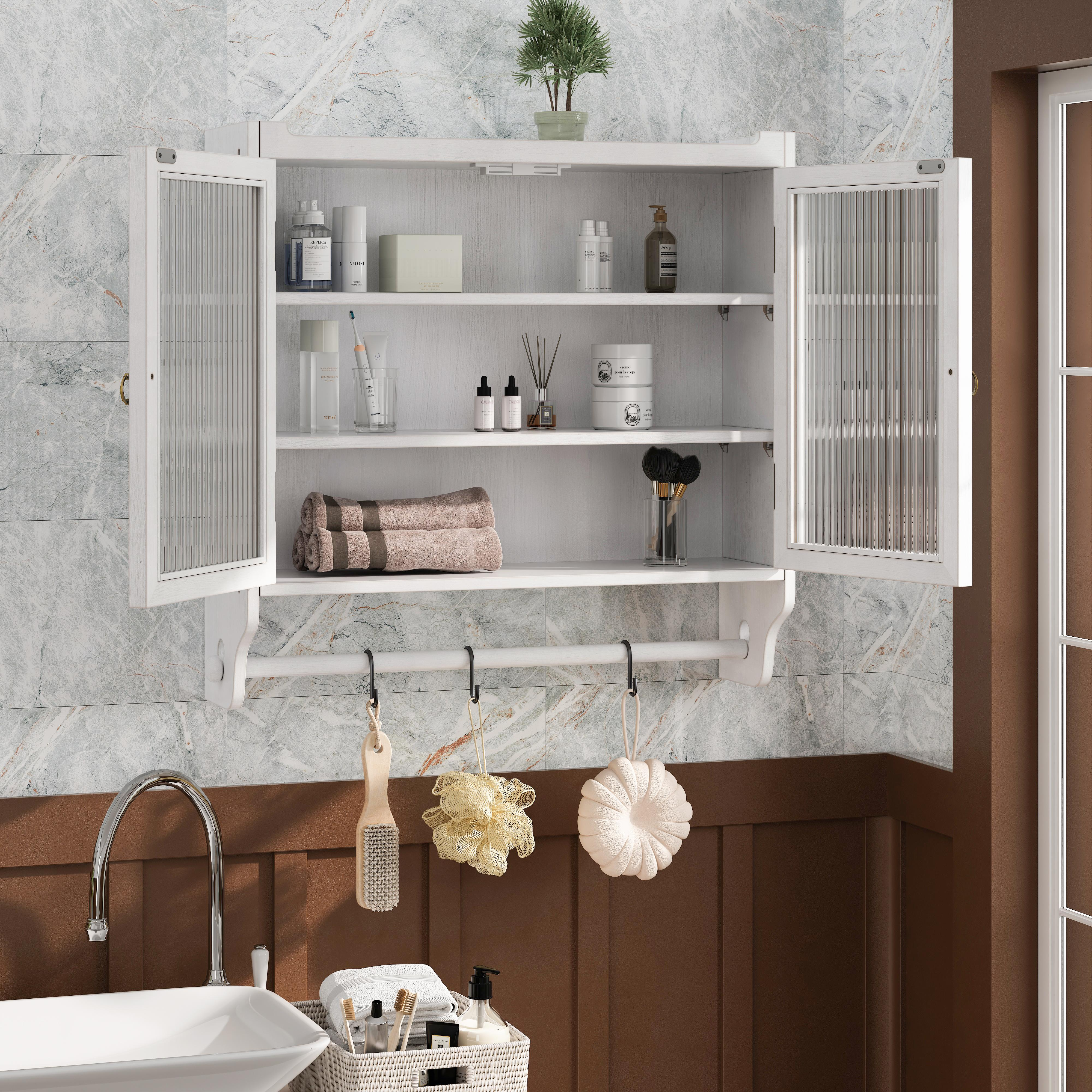 Ein Badezimmerschrank mit Glastüren ist geöffnet, mit verschiedenen Toilettenartikeln. Darunter Haken mit Badzubehör.