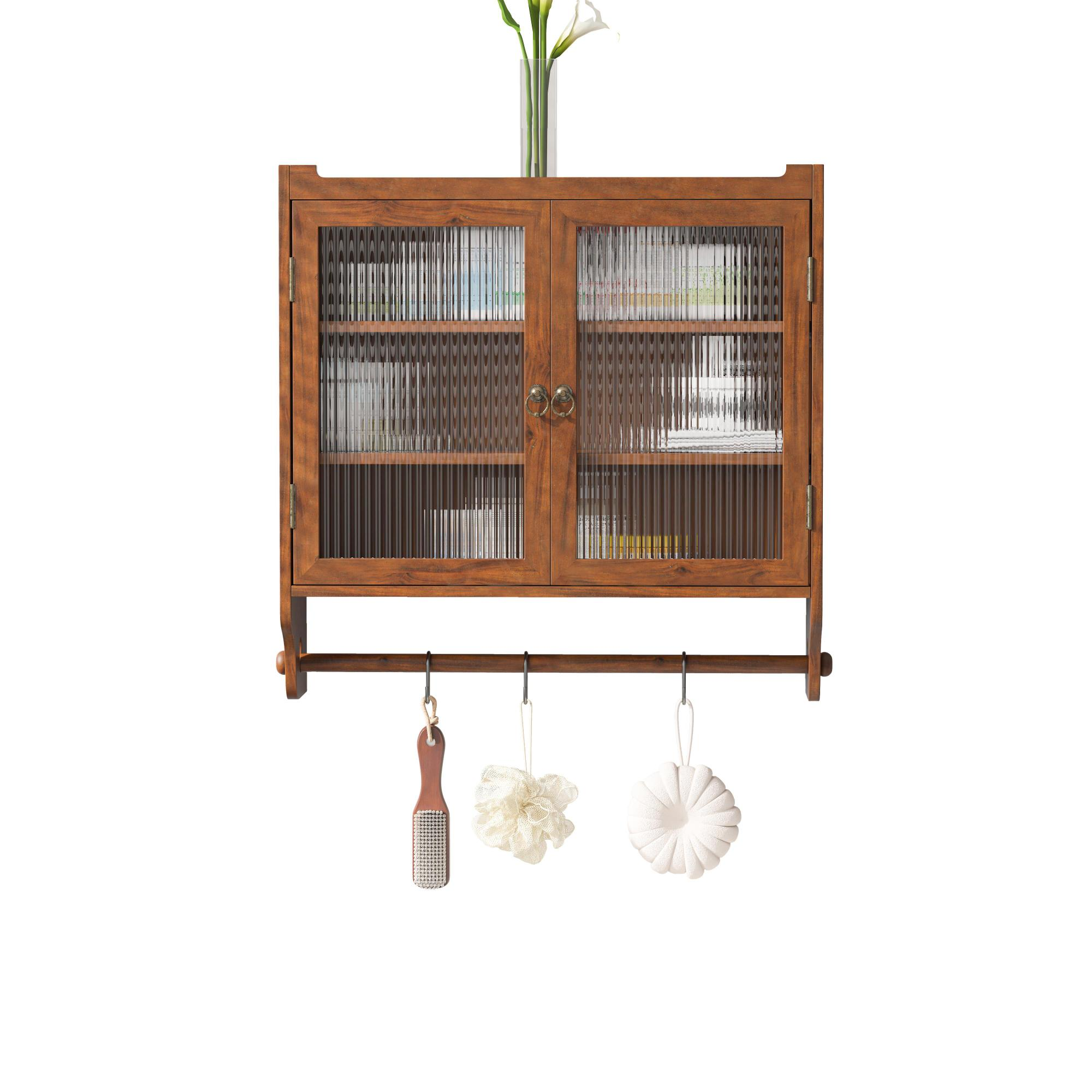 Holzschrank mit Glastüren, Handtüchern und Badartikeln darunter. Weiße Blumen in einer Glasvase oben.