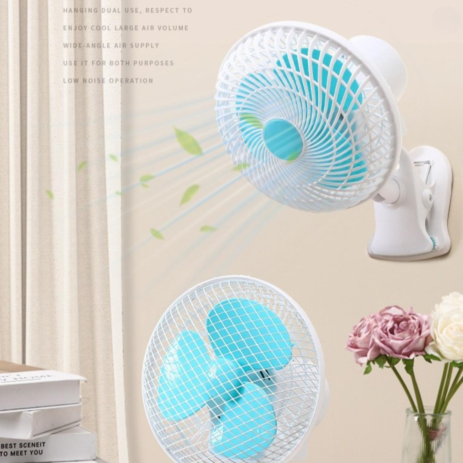 Zwei weiße und blaue Ventilatoren, einer an der Wand befestigt. Eine Blumenvase steht neben dem unteren Ventilator. Bücher sind links.