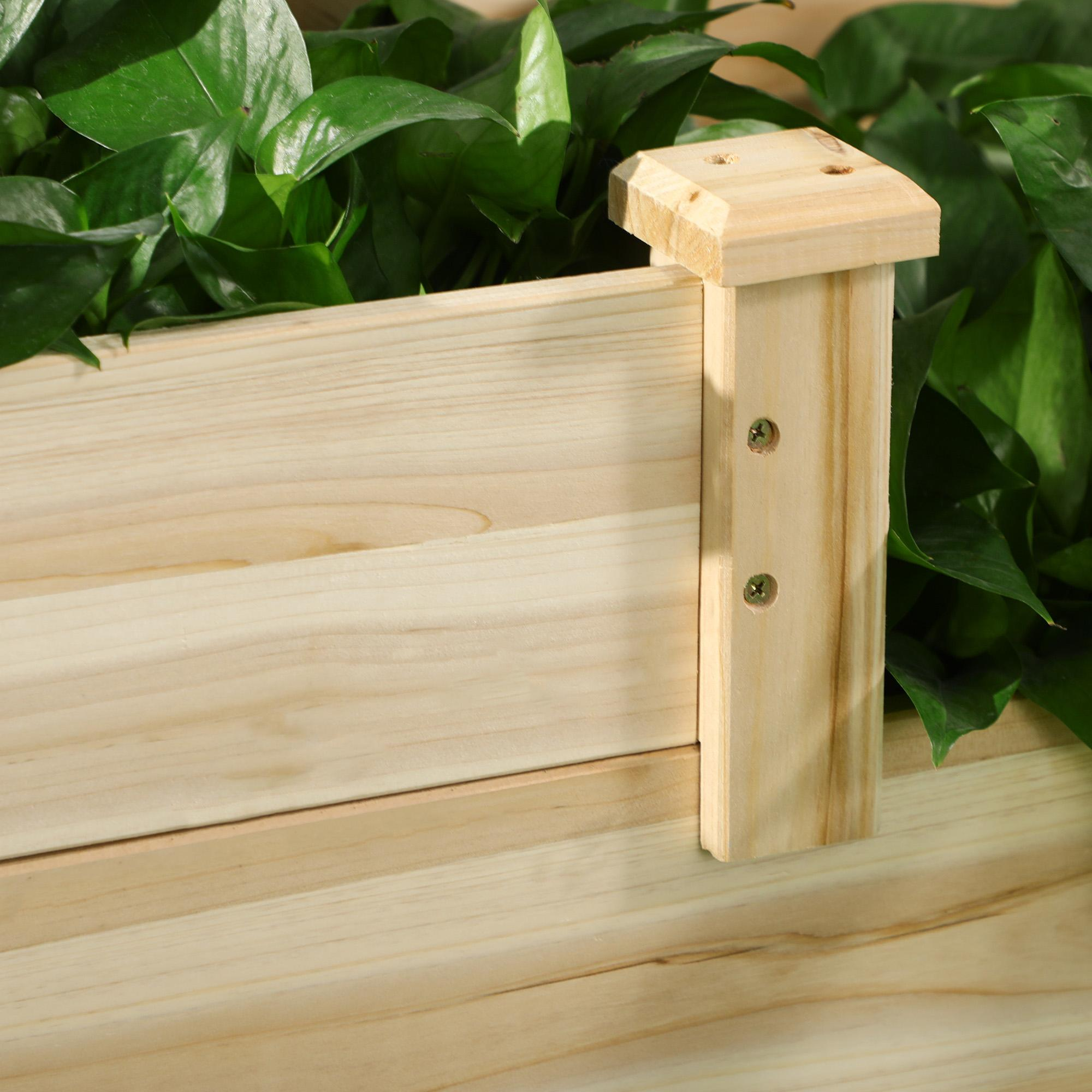 Holzpflanzer mit grünen Blättern. Helle Holzkonstruktion. Holzpfosten mit Schrauben. Blätter sind der Fokus.