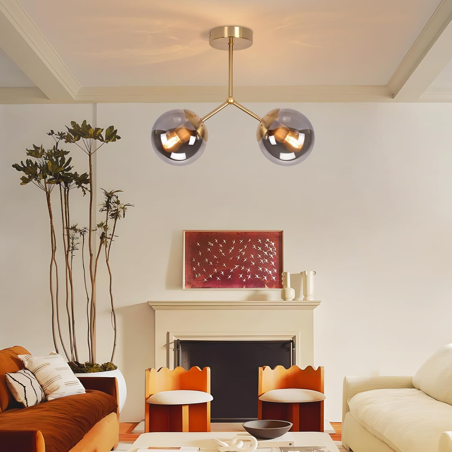 Salon z złotą oprawą oświetleniową. Dwie szklane kule wiszą z sufitu. Widoczny kominek, krzesła i sofa.
