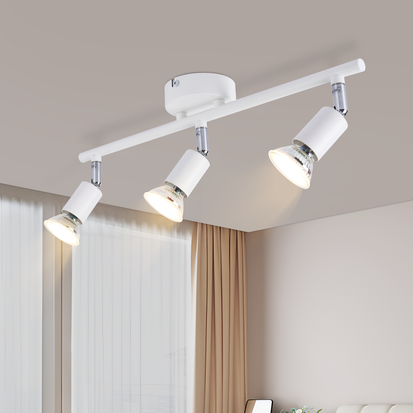 Faretto da soffitto bianco con tre luci regolabili. Tende e un divano sullo sfondo.