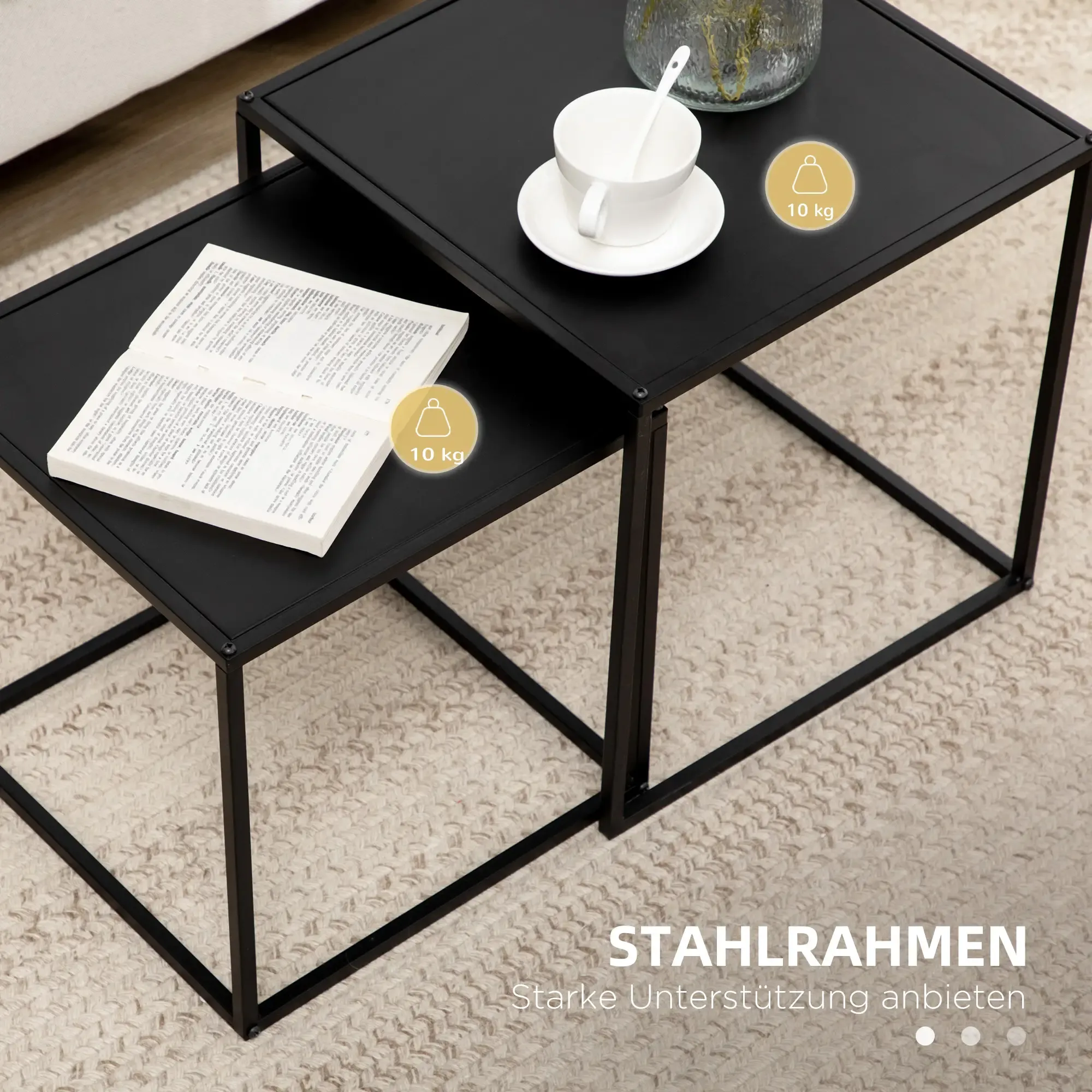 Zwei schwarze Metalltische auf einem beigefarbenen Teppich. Ein Tisch hat ein Buch, der andere eine Tasse und Untertasse.