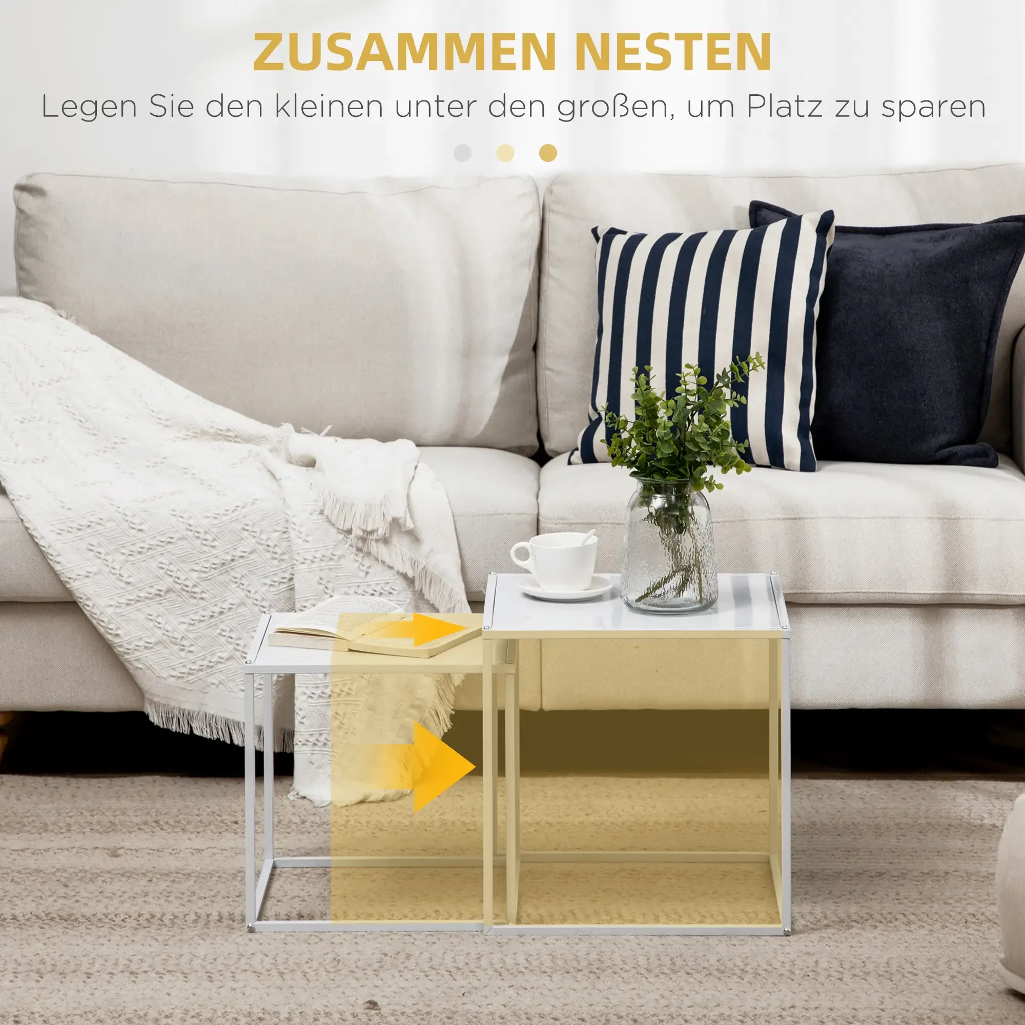 Wohnzimmer mit weißem Sofa, Kissen und Beistelltisch. Eine Vase mit Pflanzen und eine Kaffeetasse stehen auf dem Tisch.