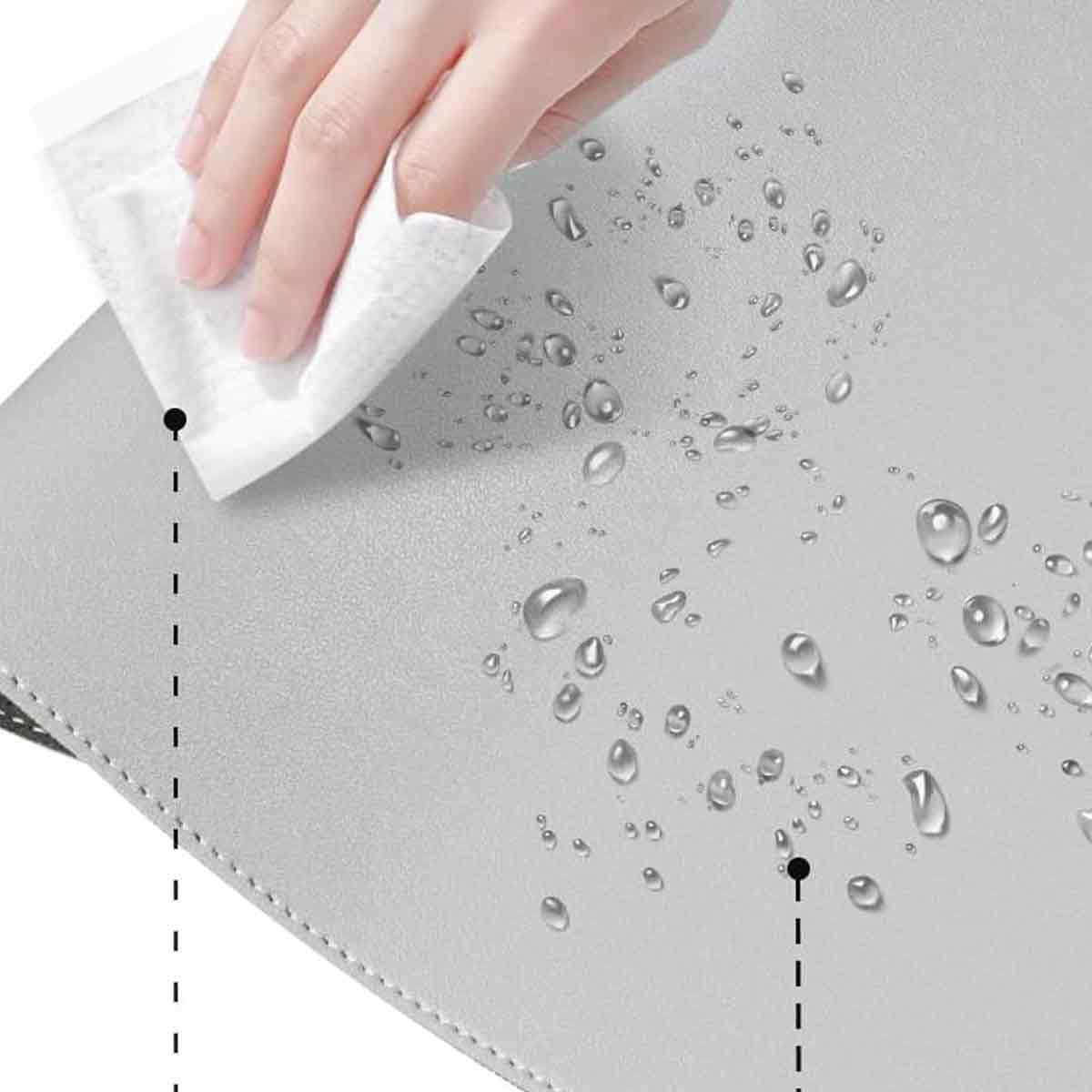 Eine Hand wischt eine graue Oberfläche mit einem weißen Tuch ab. Wassertropfen sind auf der Oberfläche verteilt. Die Oberfläche hat einen genähten Rand.