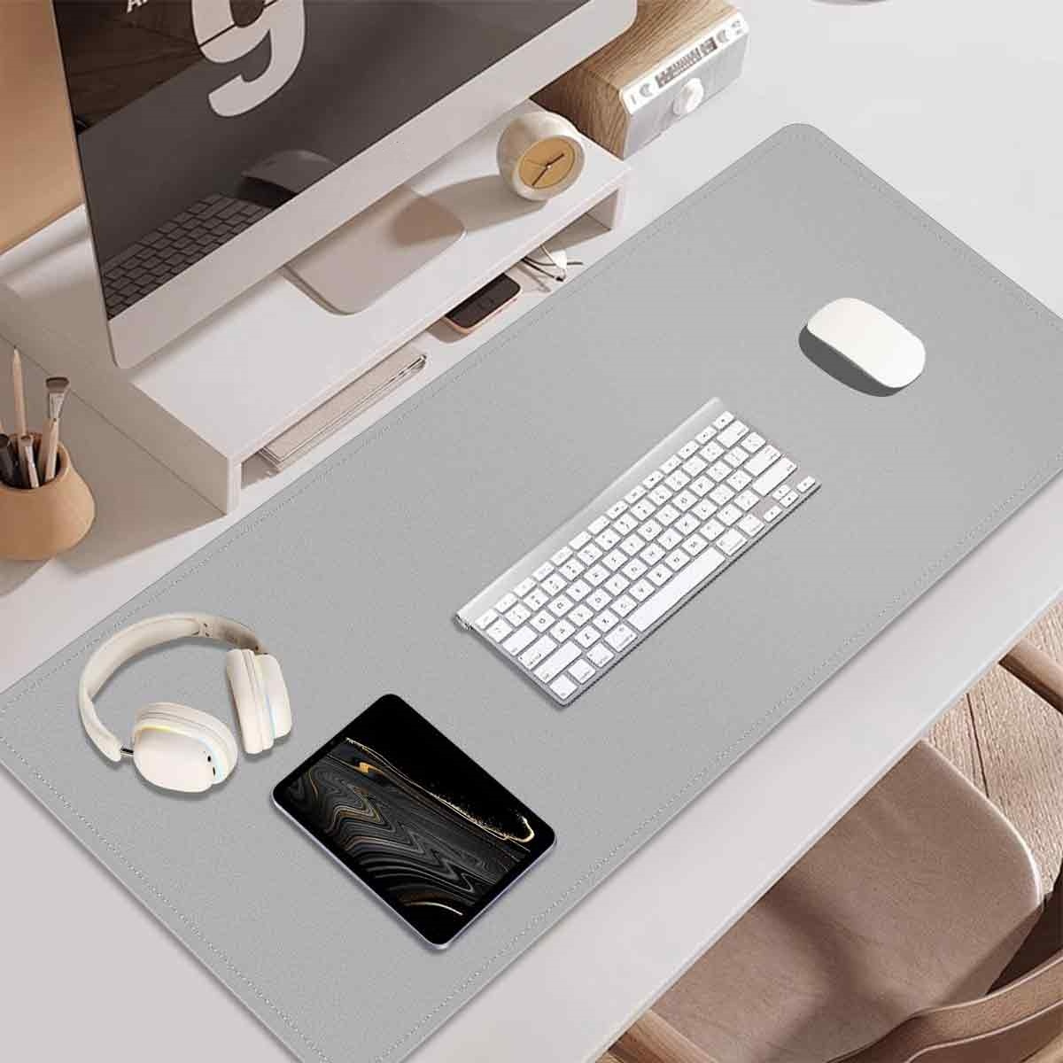 Schreibtisch-Setup: Monitor, Tastatur, Maus, Kopfhörer und Tablet auf einer grauen Matte. Der Schreibtisch ist weiß, mit Holzstuhl.