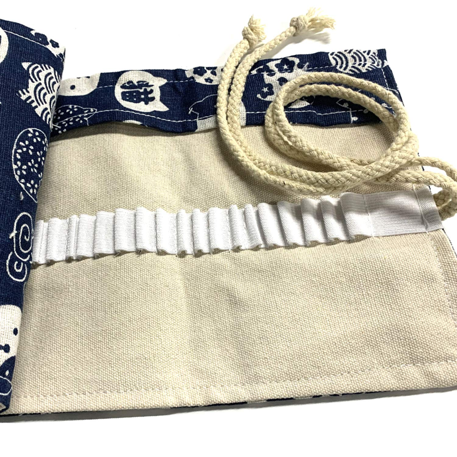 Ein offenes Stoff-Etui mit blauem Muster oben und beigem Innenraum. Weiße Gummibänder halten Stifte.
