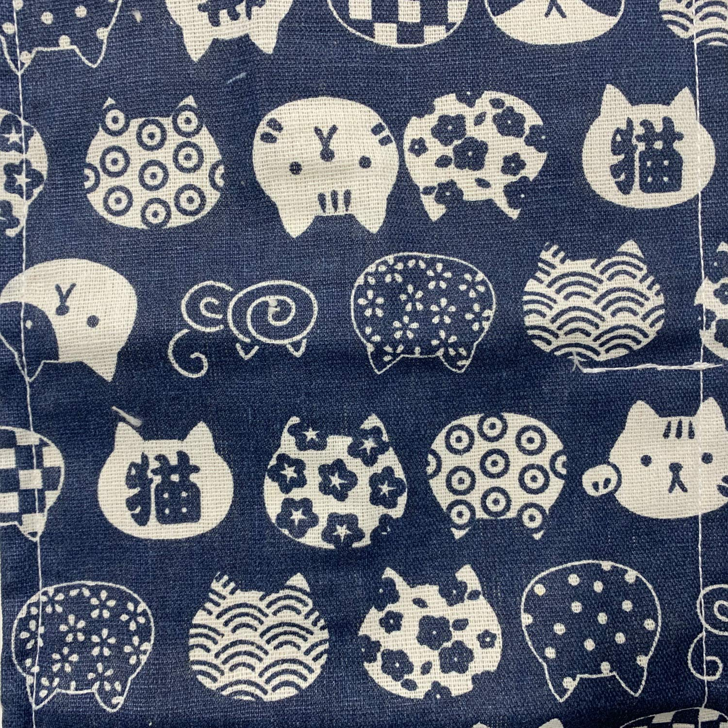 Marineblauer Stoff mit weißen Katzen- und Schweinemustern. Katzen haben verschiedene Muster wie Kreise oder Blumen. Schweine haben einfache Designs.