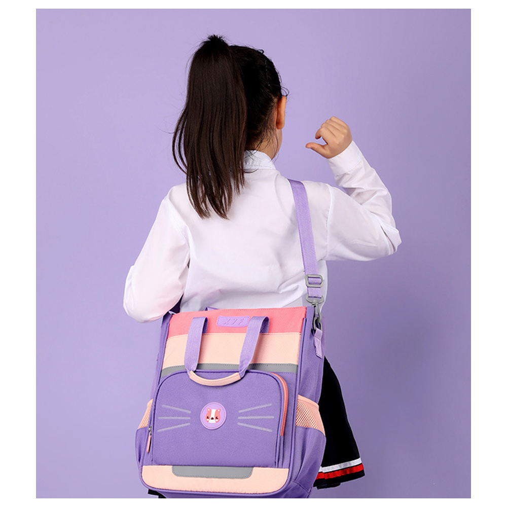 Ein Mädchen mit Pferdeschwanz trägt ein weißes Hemd und eine Schultasche. Die Tasche ist lila, rosa und hat ein Katzengesicht.