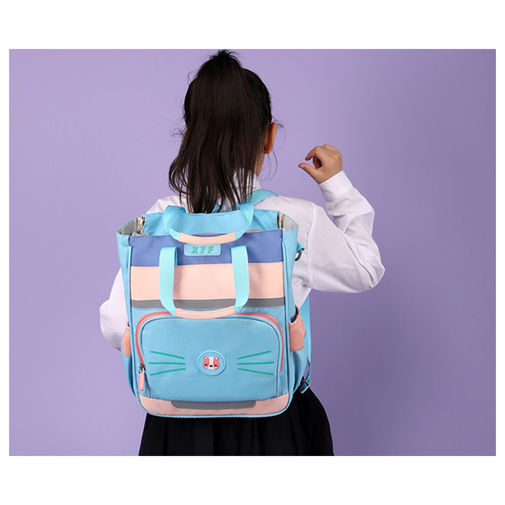 Ein Kind, das einen blauen Rucksack mit Katzengesicht trägt. Das Kind ist abgewandt und trägt ein weißes Hemd und einen schwarzen Rock.