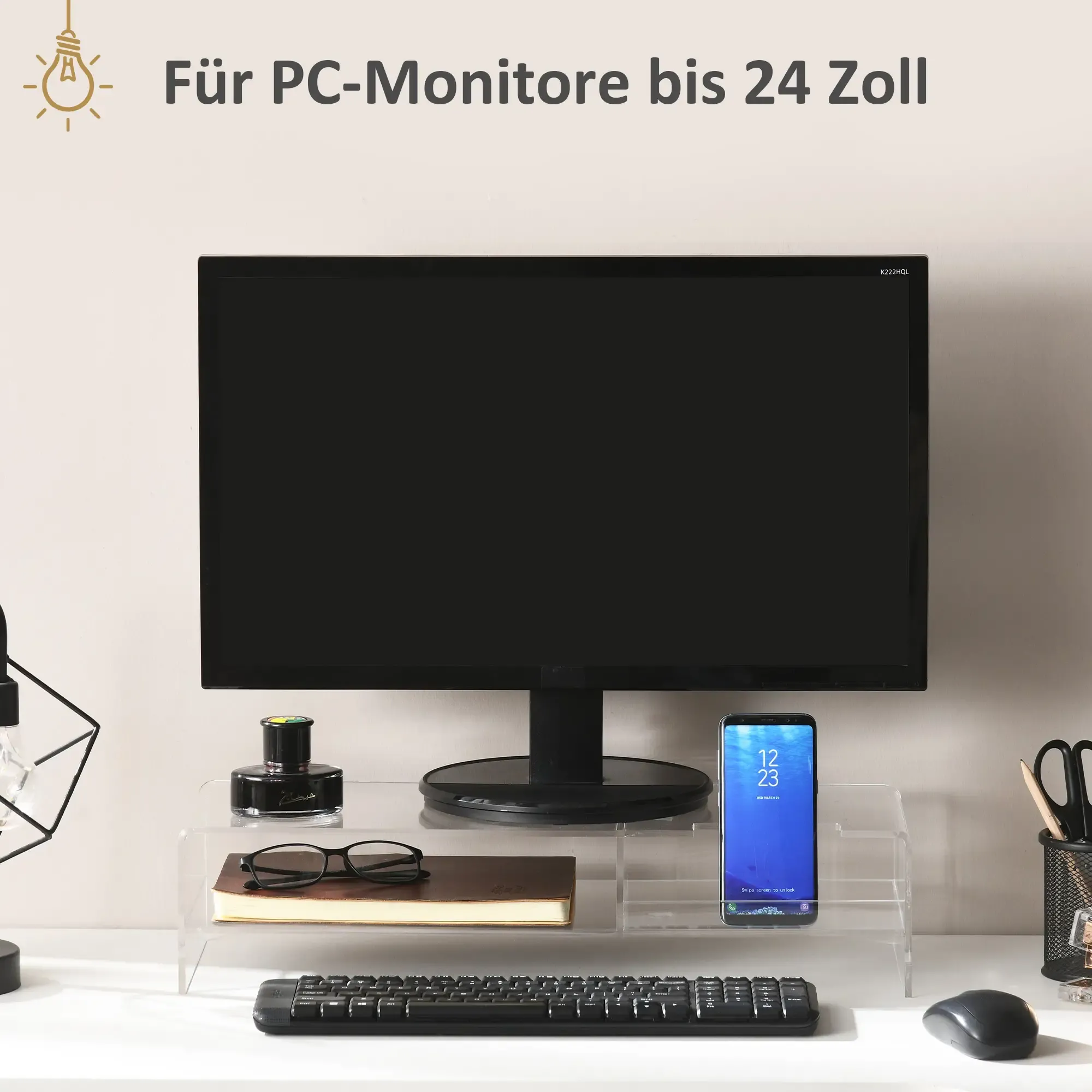Ein Monitor steht auf einem transparenten Ständer mit Telefon, Brille und Tastatur.