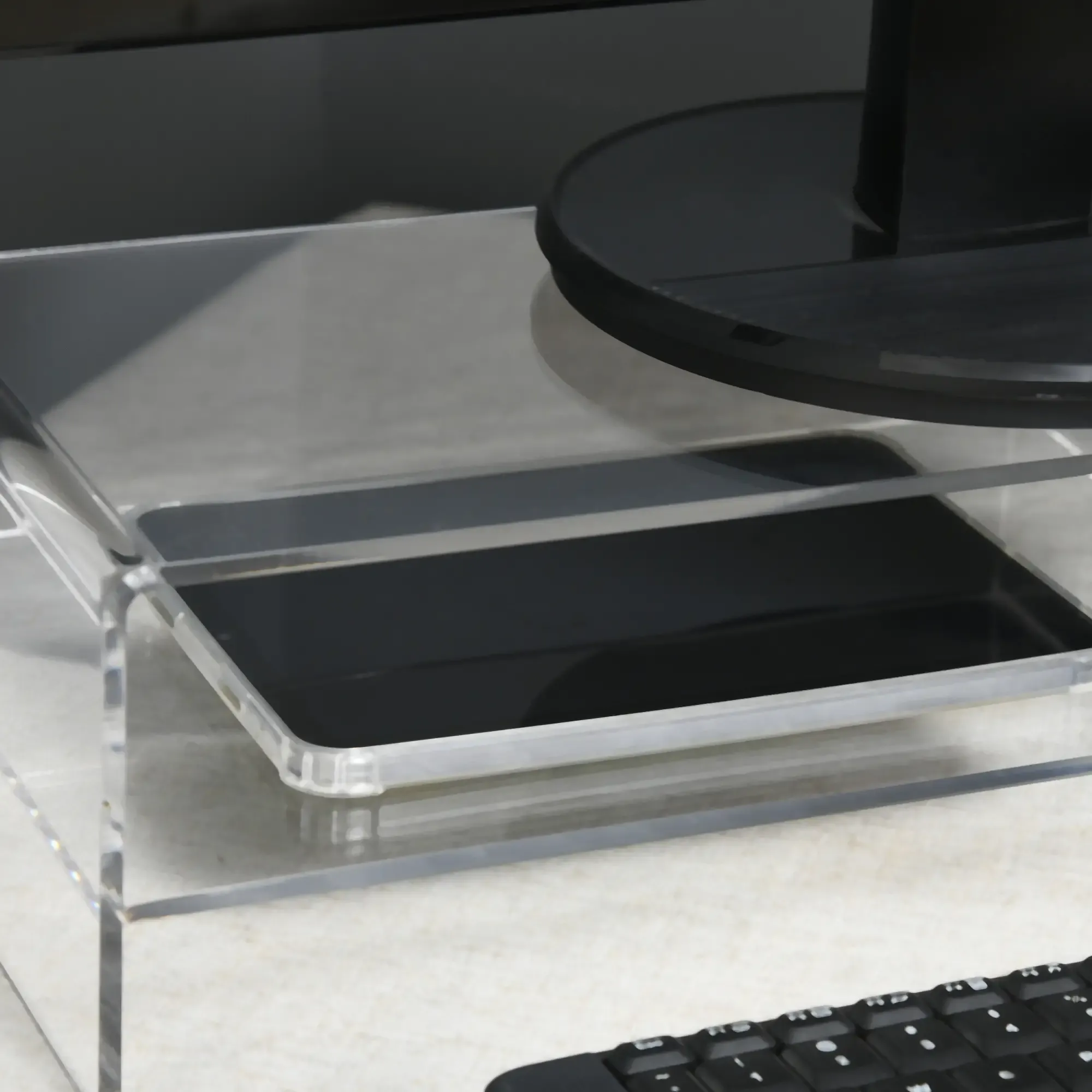 Transparenter Schreibtisch-Organizer mit schwarzem Rechteck und Monitor. Eine Tastatur ist im Vordergrund zu sehen.