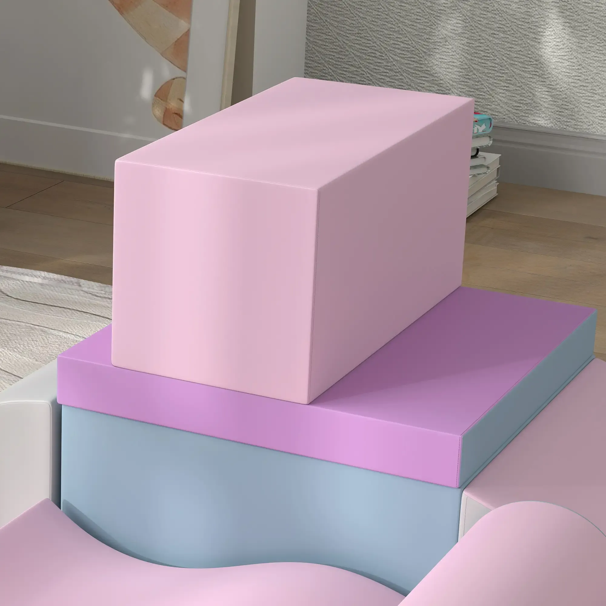 Ein Stapel bunter Blöcke: Rosa, Lila und Hellblau. Die Szene spielt auf einem Holzboden mit einer weißen Wand und einem Gemälde.