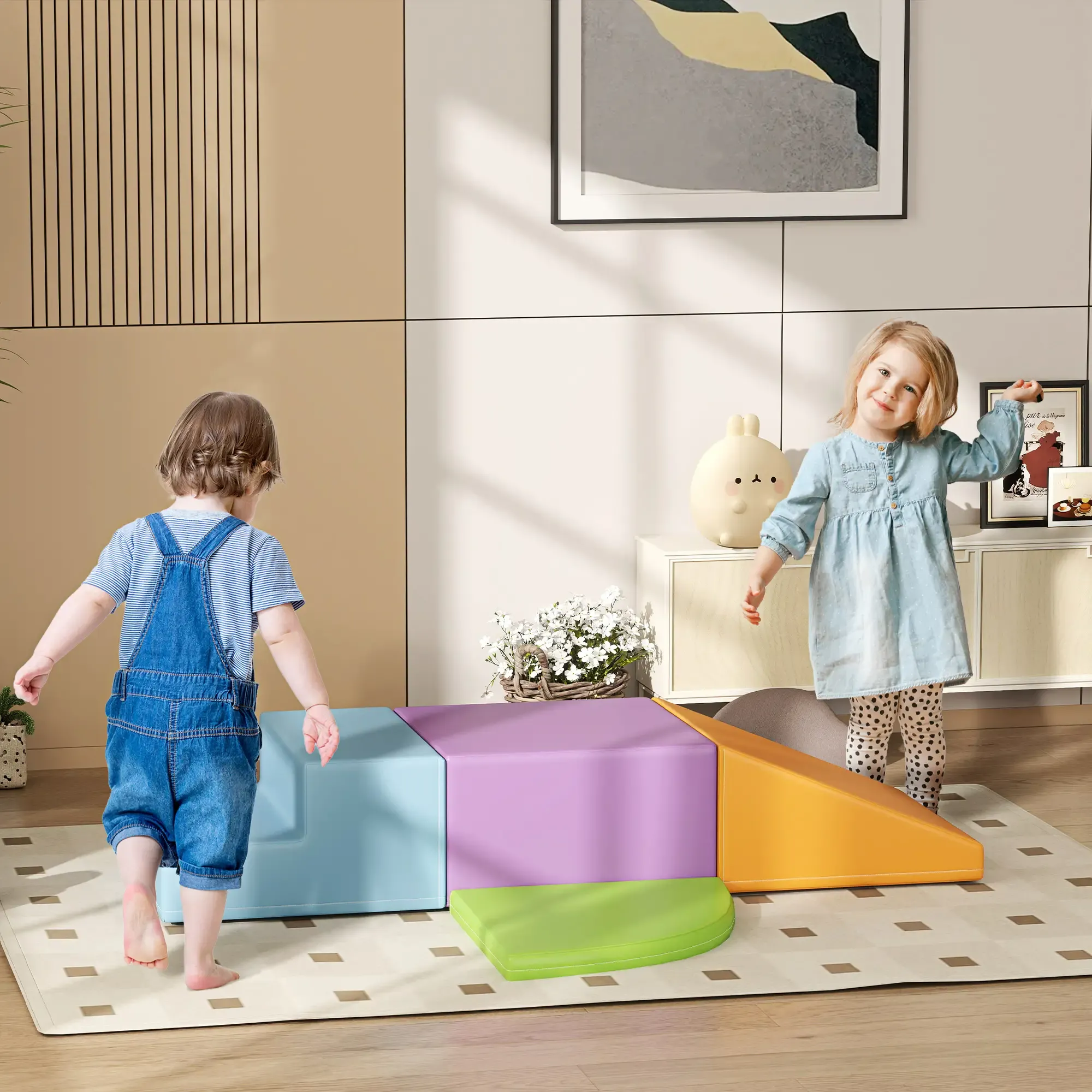 Zwei Kinder spielen in der Nähe von bunten Schaumstoffblöcken. Eines trägt eine Jeanslatzhose, das andere ein blaues Kleid. Eine weiße Hasenlampe ist sichtbar.