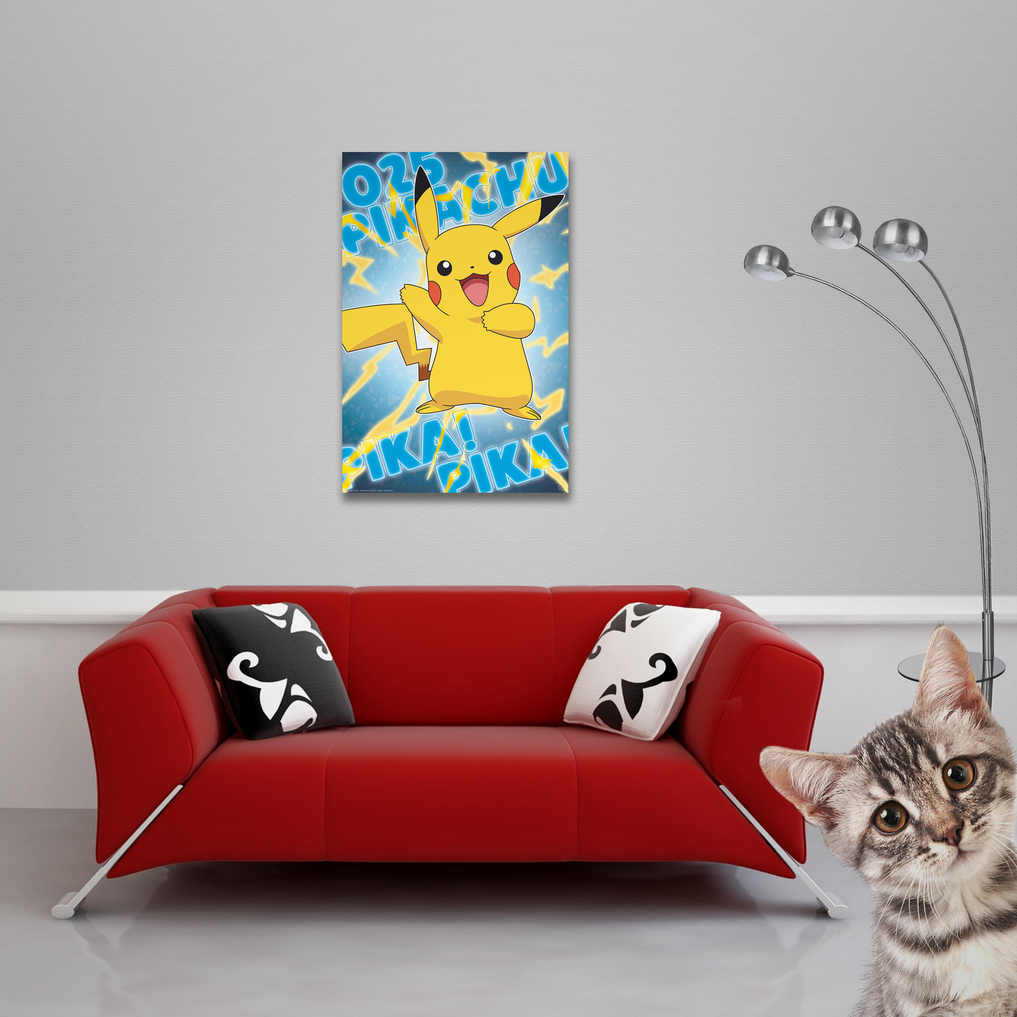 Rotes Sofa mit zwei Kissen und einem Pikachu-Poster. Eine Katze schaut in die Kamera.
