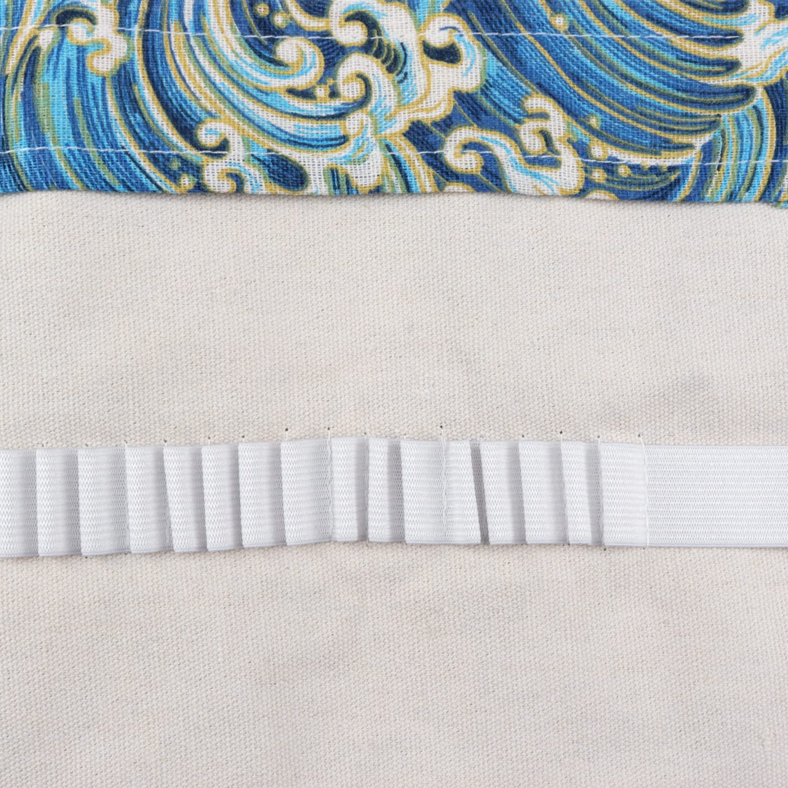 Oben: blauer Wellenstoff. Mitte: cremefarbener Stoff. Unten: weißes, plissiertes Gummiband.