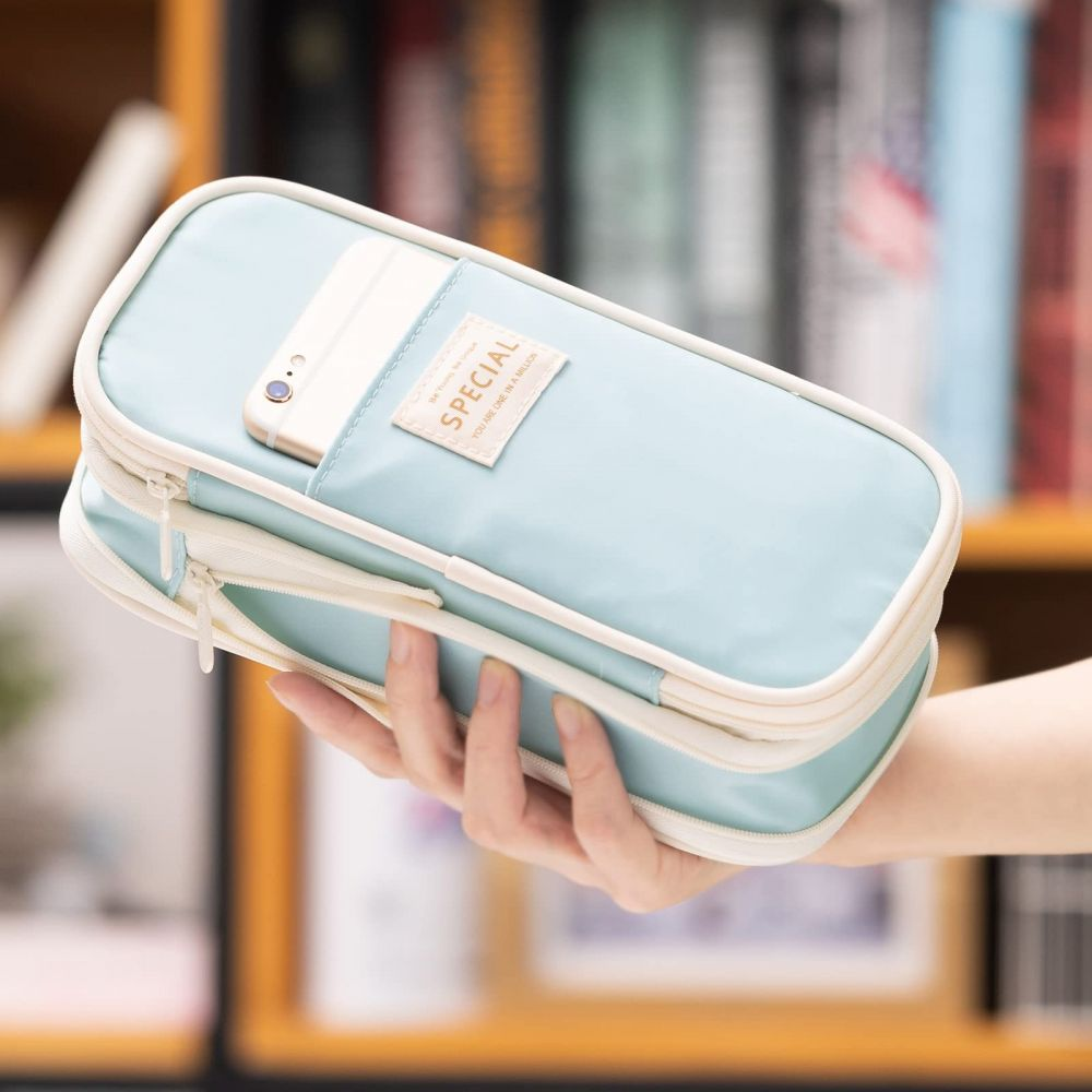 Eine Hand hält ein hellblaues Federmäppchen mit einem Telefon darin. Auf dem Etui steht "SPECIAL". Im Hintergrund sind Bücher zu sehen.