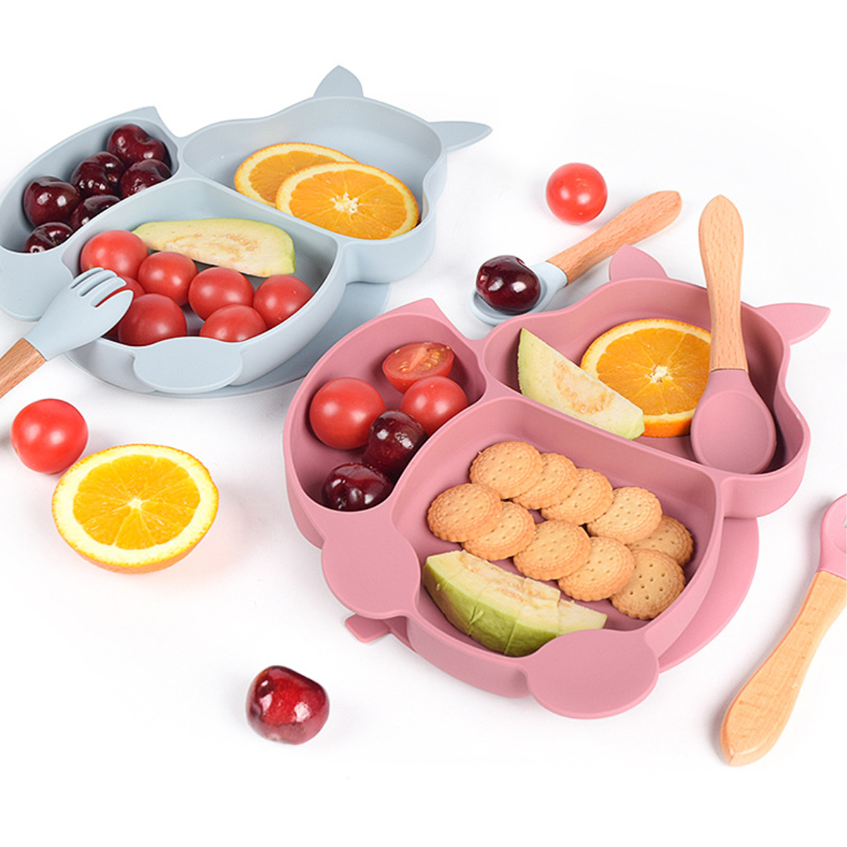 Zwei Babyteller mit Essen: Kirschen, Orangenscheiben, Tomaten, Kekse und Melone. HolzLöffel und Gabeln sind enthalten.