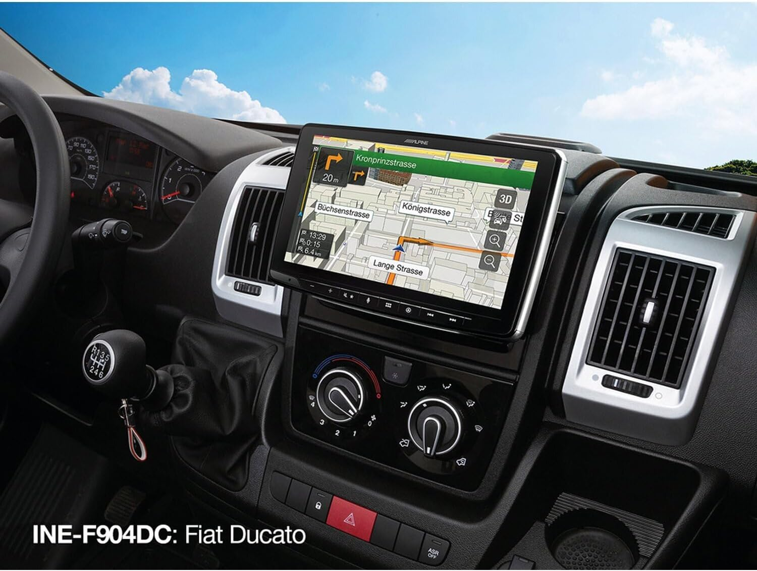 Autointerieur mit Navigationsbildschirm, der eine Karte zeigt, Lenkrad, Schalthebel und Lüftungsschlitze. Der Himmel ist durch die Windschutzscheibe sichtbar.