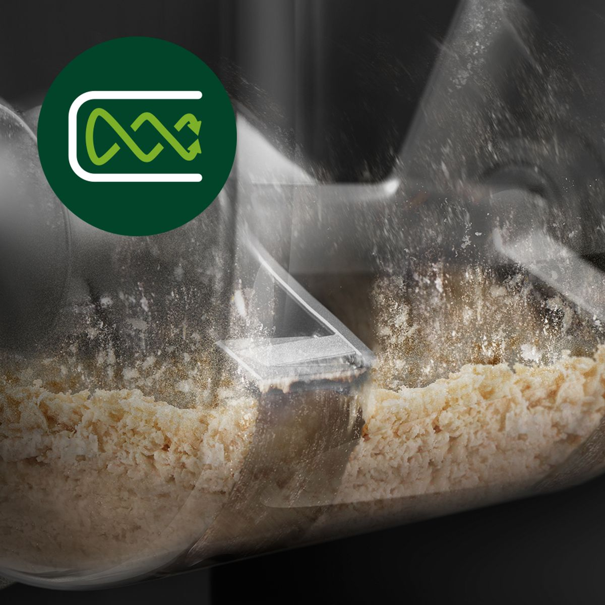 Zbliżenie robota kuchennego w akcji. Beżowe jedzenie jest przetwarzane, z zielonym okrągłym logo w lewym górnym rogu.