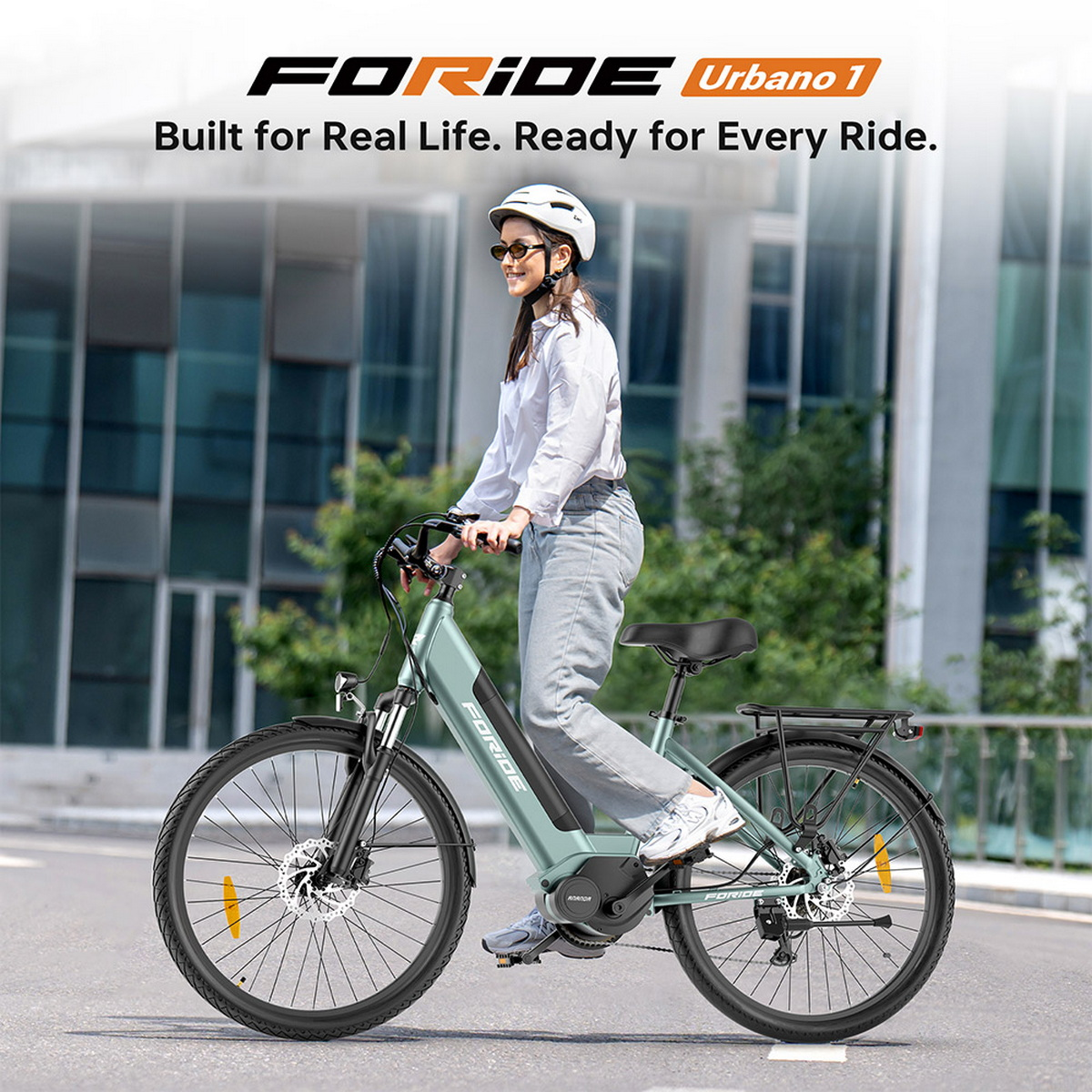 Kobieta jedzie zielonym rowerem elektrycznym po drodze. Ma na sobie kask i okulary przeciwsłoneczne. W tle znajdują się budynki i drzewa.