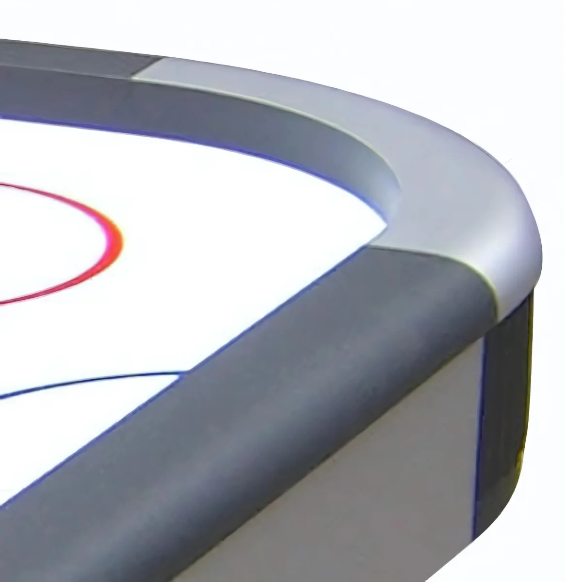 Close-up of an air hockey table corner. Gray and silver borders frame the white playing surface with red and blue markings.