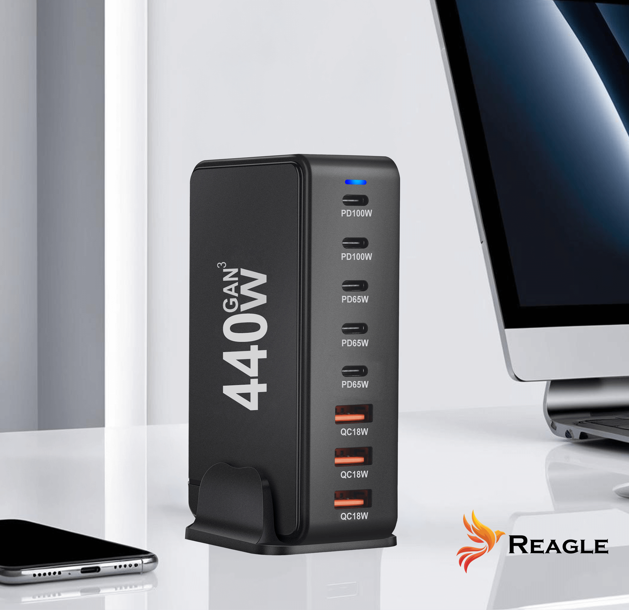 Czarna ładowarka 440W GAN z wieloma portami, telefonem i monitorem na białej powierzchni. Widoczne logo.