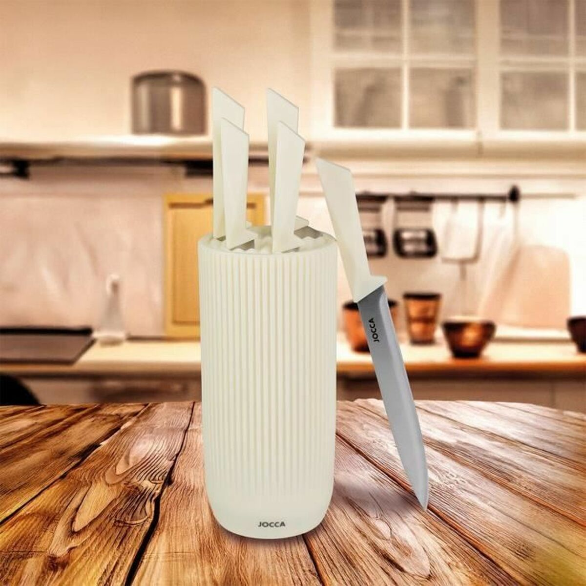 Ein Messerset auf einem Holztisch. Ein weißer Messerhalter mit Messern und ein Messer, das sich daran lehnt. Küchenhintergrund.