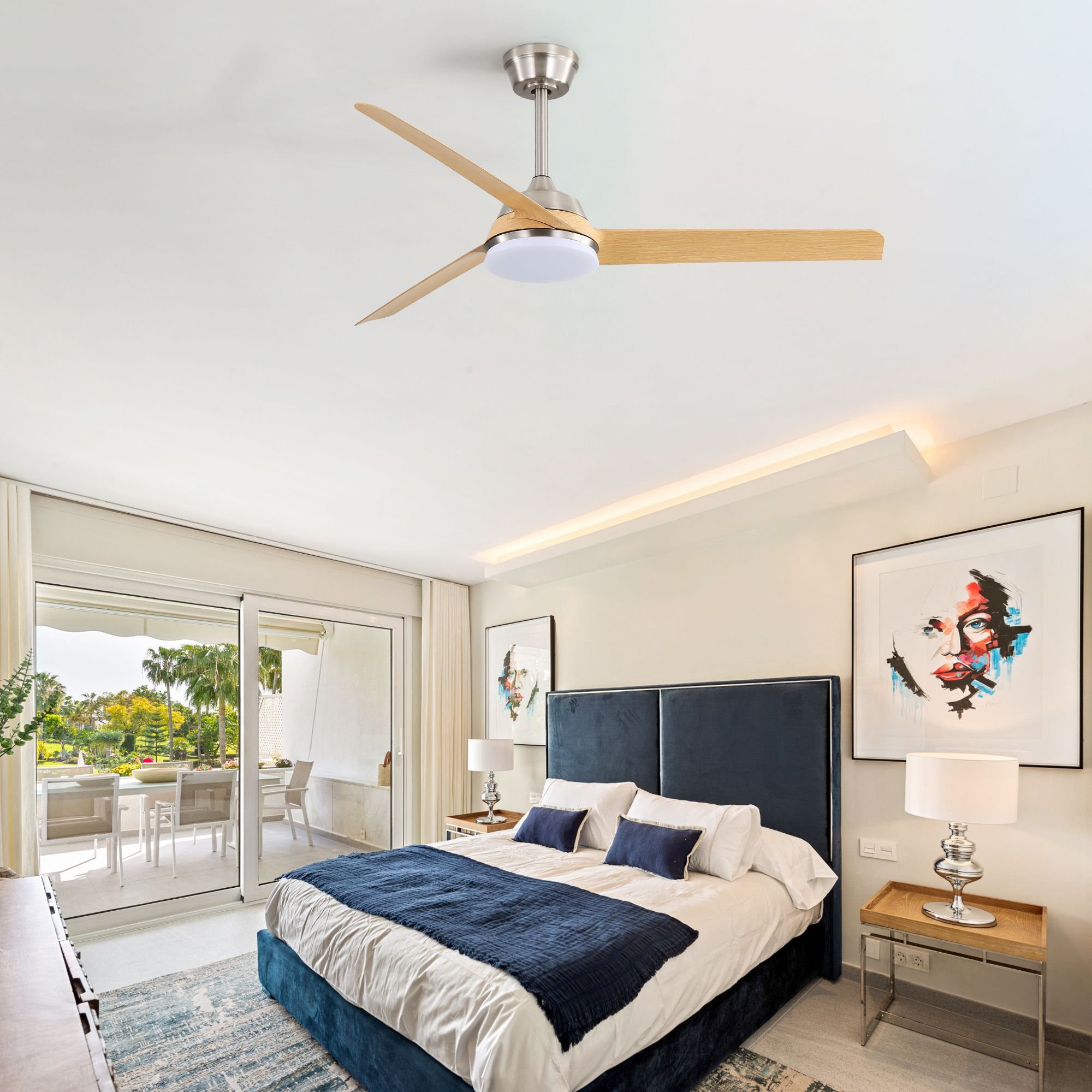 Schlafzimmer mit Deckenventilator, Bett, Kunstwerk und offenen Türen zu einer Terrasse. Heller, luftiger Raum mit Blick auf Palmen.