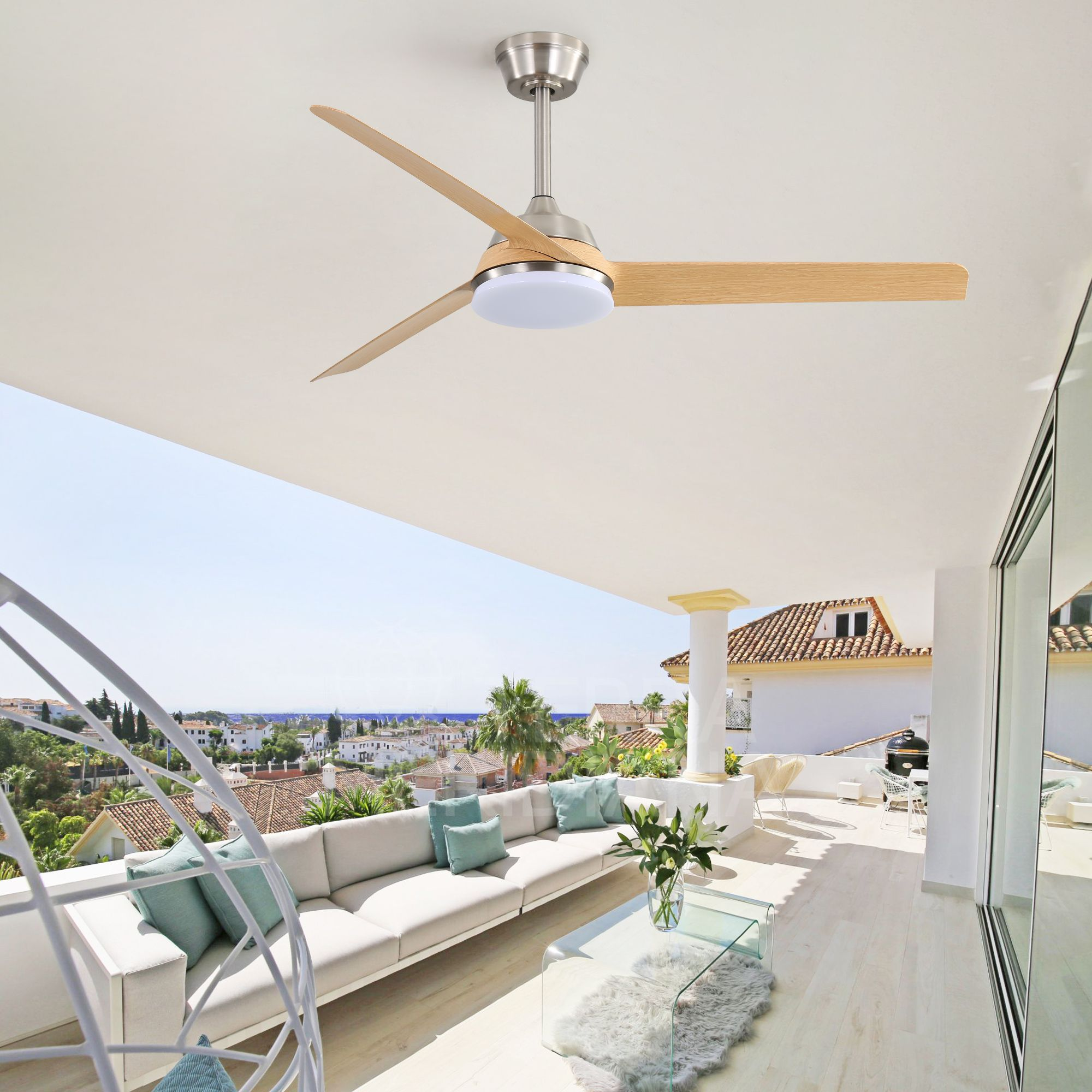 Ein Deckenventilator mit Holzflügeln hängt über einem Balkon. Der Balkon hat ein weißes Sofa, einen Glastisch und Blick auf die Stadt.