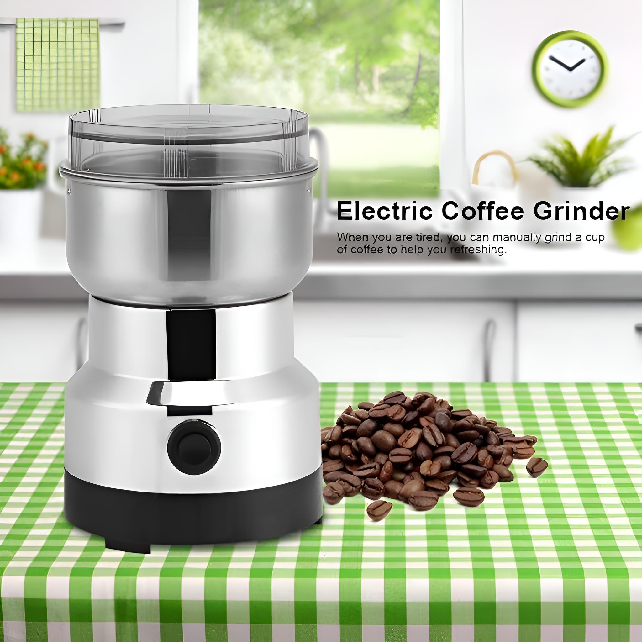 Elektrische Kaffeemühle, Stahlkörper, schwarzer Sockel, auf grün-karierter Tischdecke, mit Kaffeebohnen.