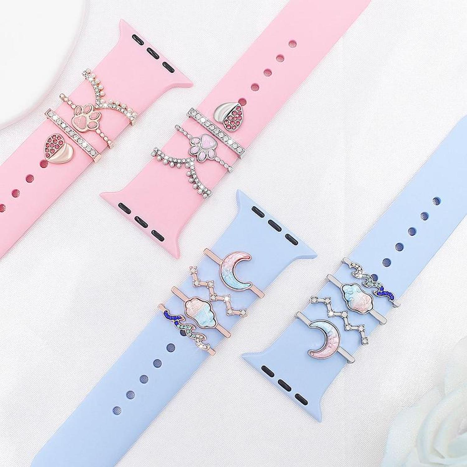 Drei Armbänder: rosa und blau. Sie haben dekorative Anhänger wie Pfotenabdrücke, Herzen und Monde mit Kristallen.