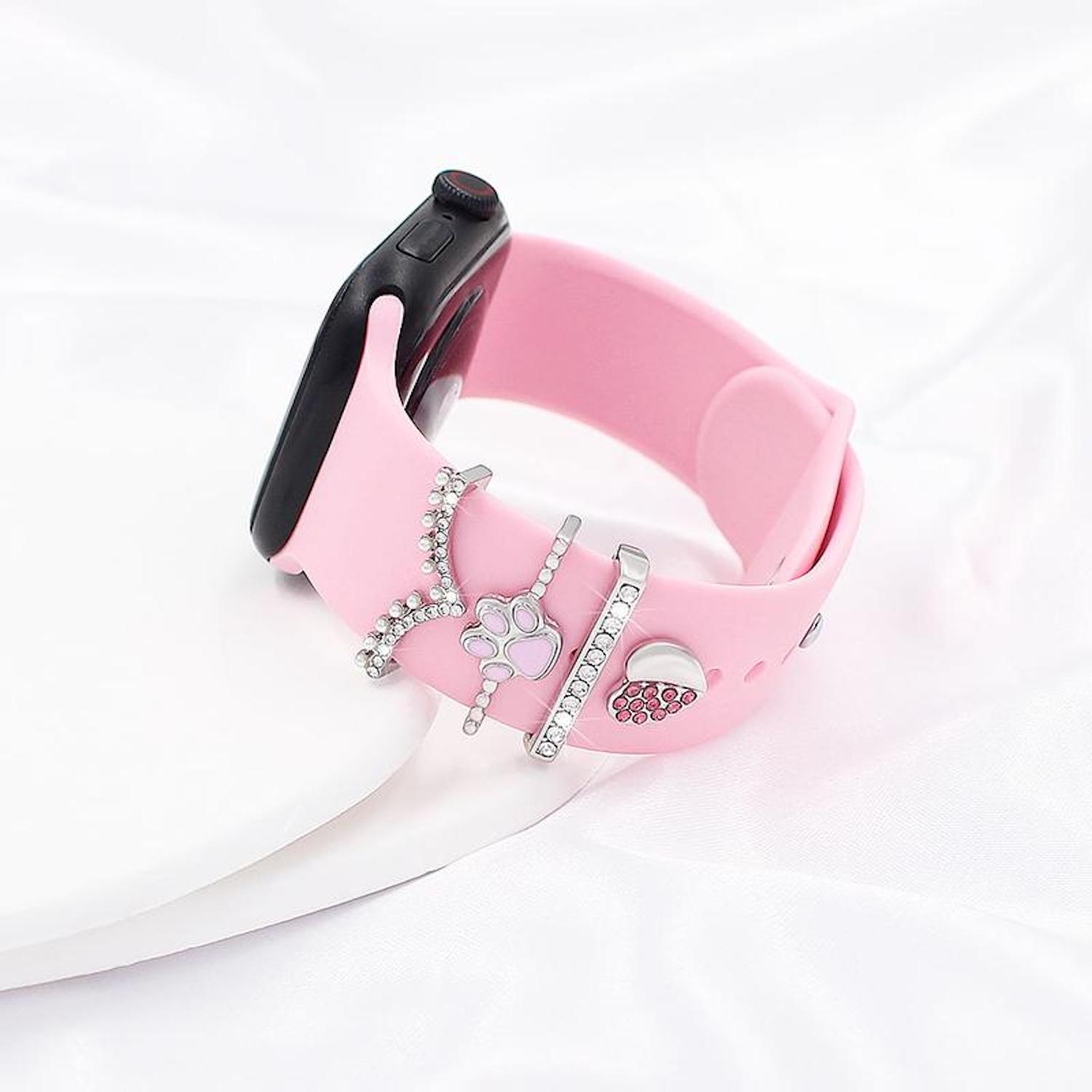 Ein rosa Smartwatch-Armband mit dekorativen Anhängern. Das Zifferblatt ist schwarz. Zu den Anhängern gehören ein Pfotenabdruck, ein Herz und Kristalle.