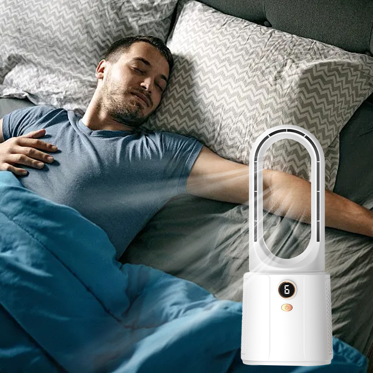 Ein Mann schläft im Bett, ein Ventilator bläst Luft. Er liegt unter einer blauen Decke. Kissen und Bettwäsche im Hintergrund.