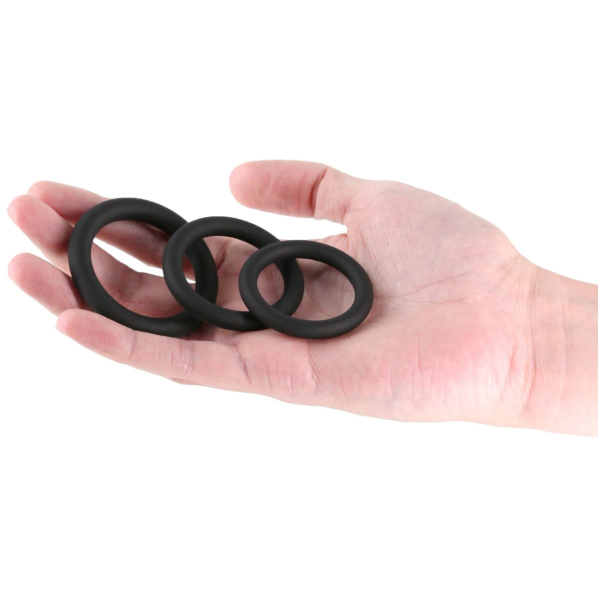 Eine Hand hält drei schwarze Gummiringe verschiedener Größen. Die Ringe befinden sich auf weißem Hintergrund.