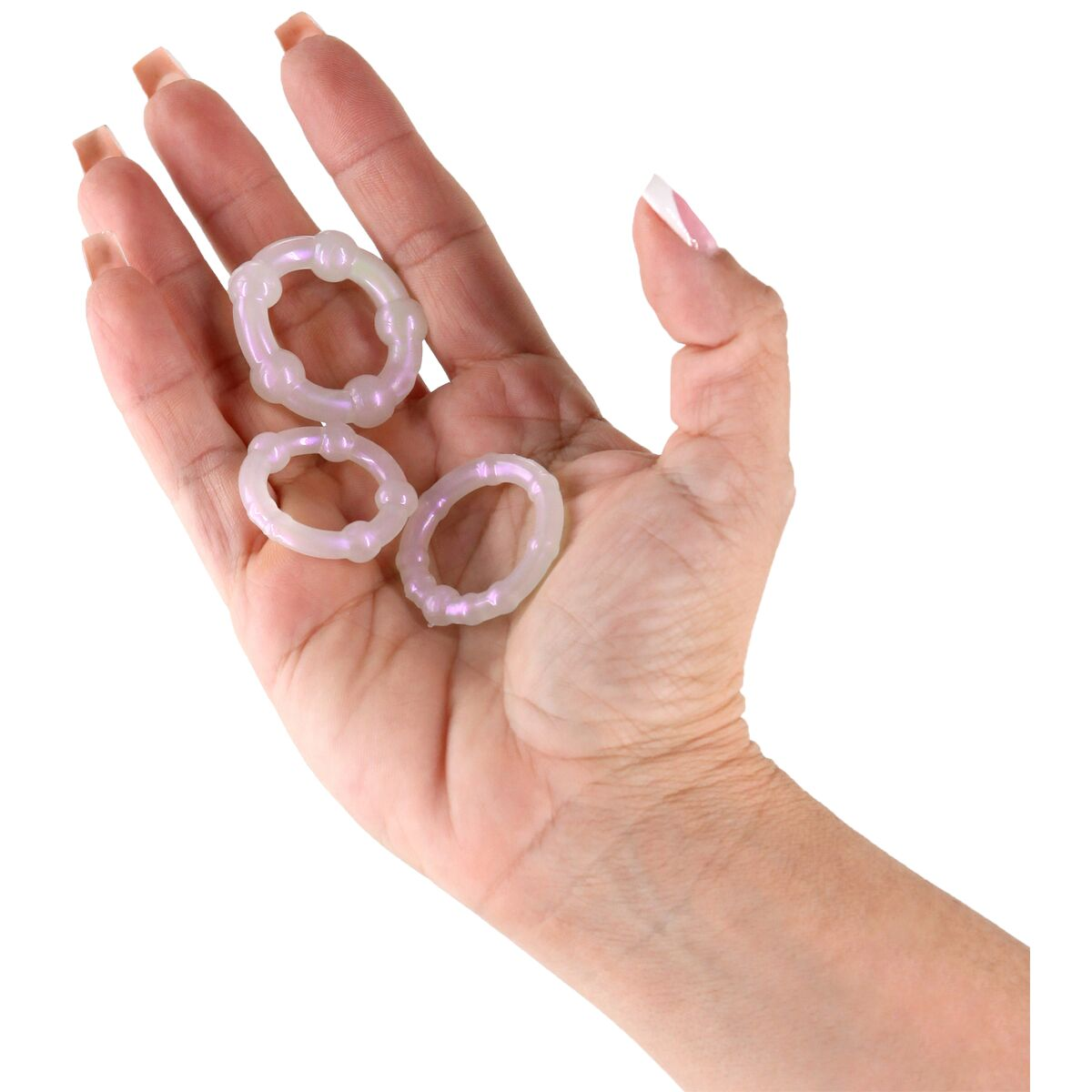Eine Hand hält drei durchscheinende, perlmuttfarbene Ringe. Die Ringe haben eine strukturierte Oberfläche. Die Hand hat manikürte Nägel.