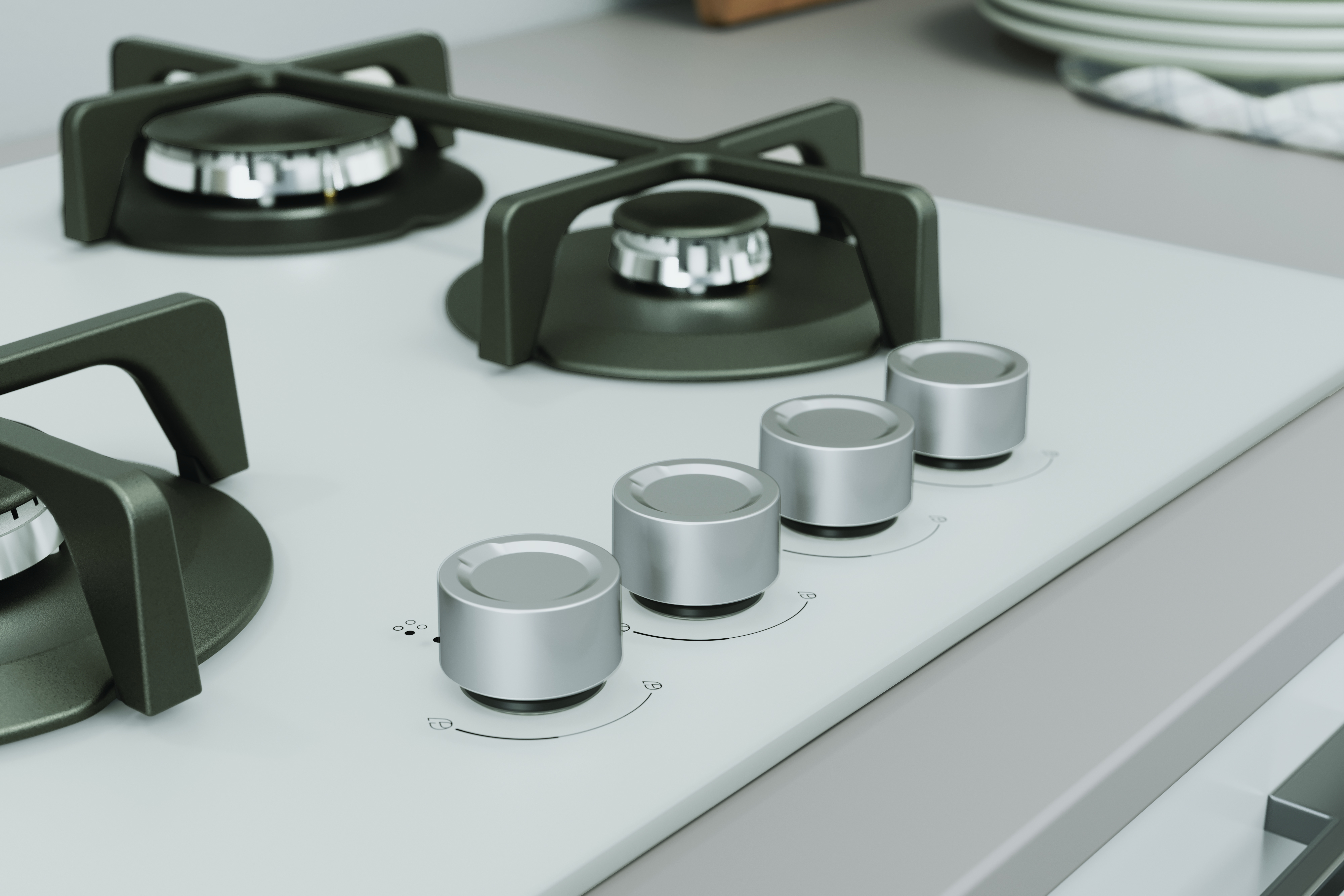 Zbliżenie szarej płyty kuchennej z czterema srebrnymi pokrętłami. Widoczne są dwa palniki. Talerze i ręcznik w tle.