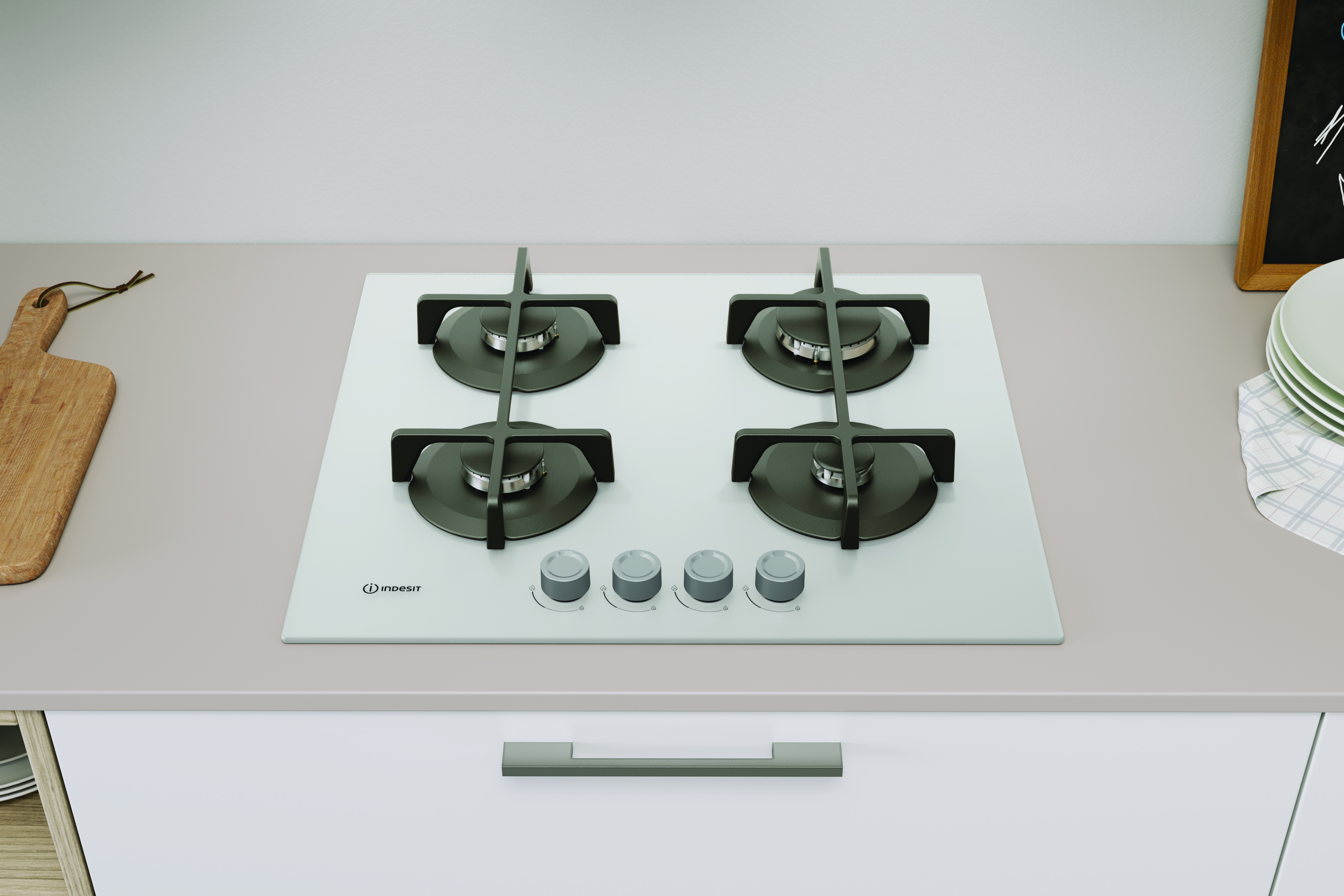 Biała kuchenka gazowa z czterema palnikami stoi na blacie. Deska do krojenia jest po lewej. Talerze po prawej.