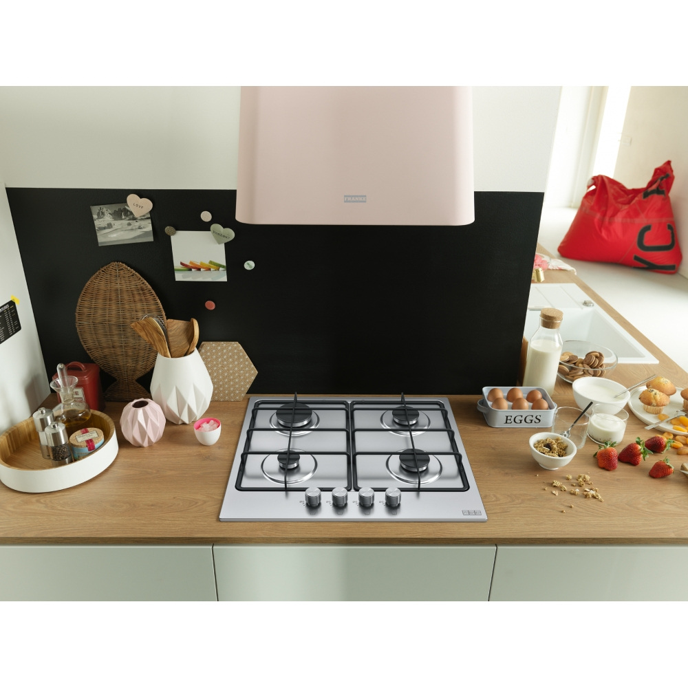 Scena di cucina con fornello, alimenti come uova, fragole e latte. Una cappa rosa e un muro nero sono visibili.