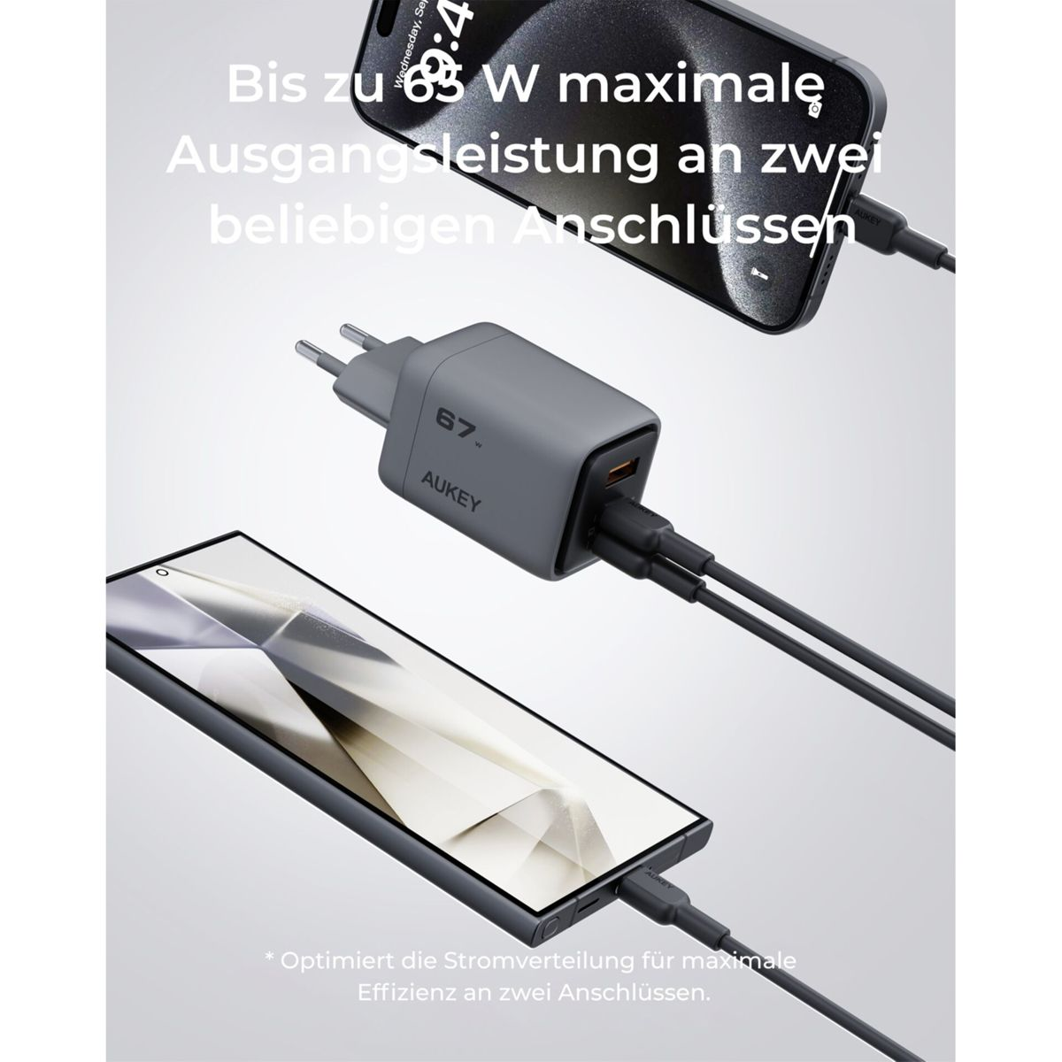 Un cargador Aukey gris con dos teléfonos conectados. Texto: Hasta 63 W máx. salida en dos puertos. Optimiza la distribución de energía.