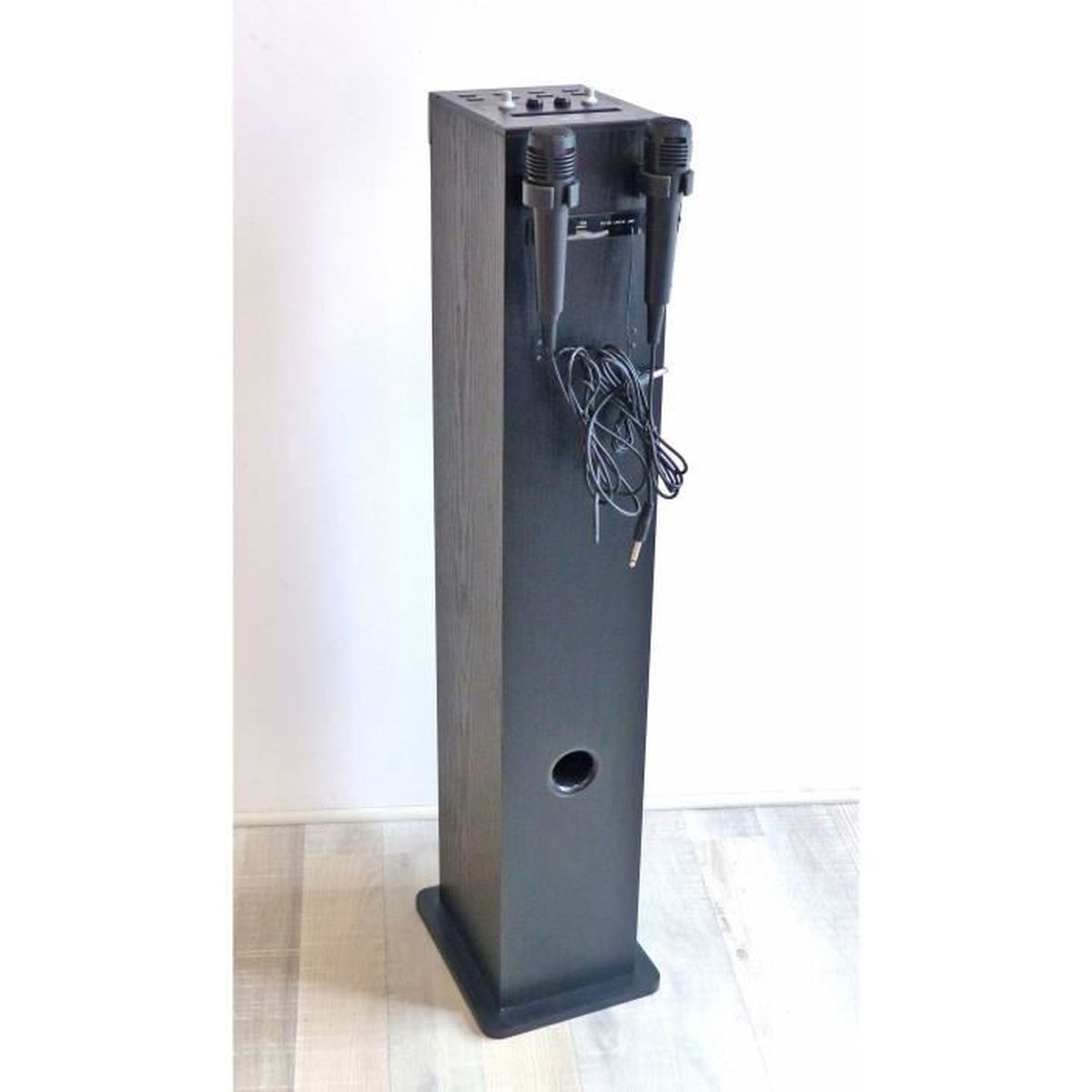 Una macchina per karaoke nera con due microfoni. Ha una forma alta e rettangolare con un foro per l'altoparlante e controlli in alto.